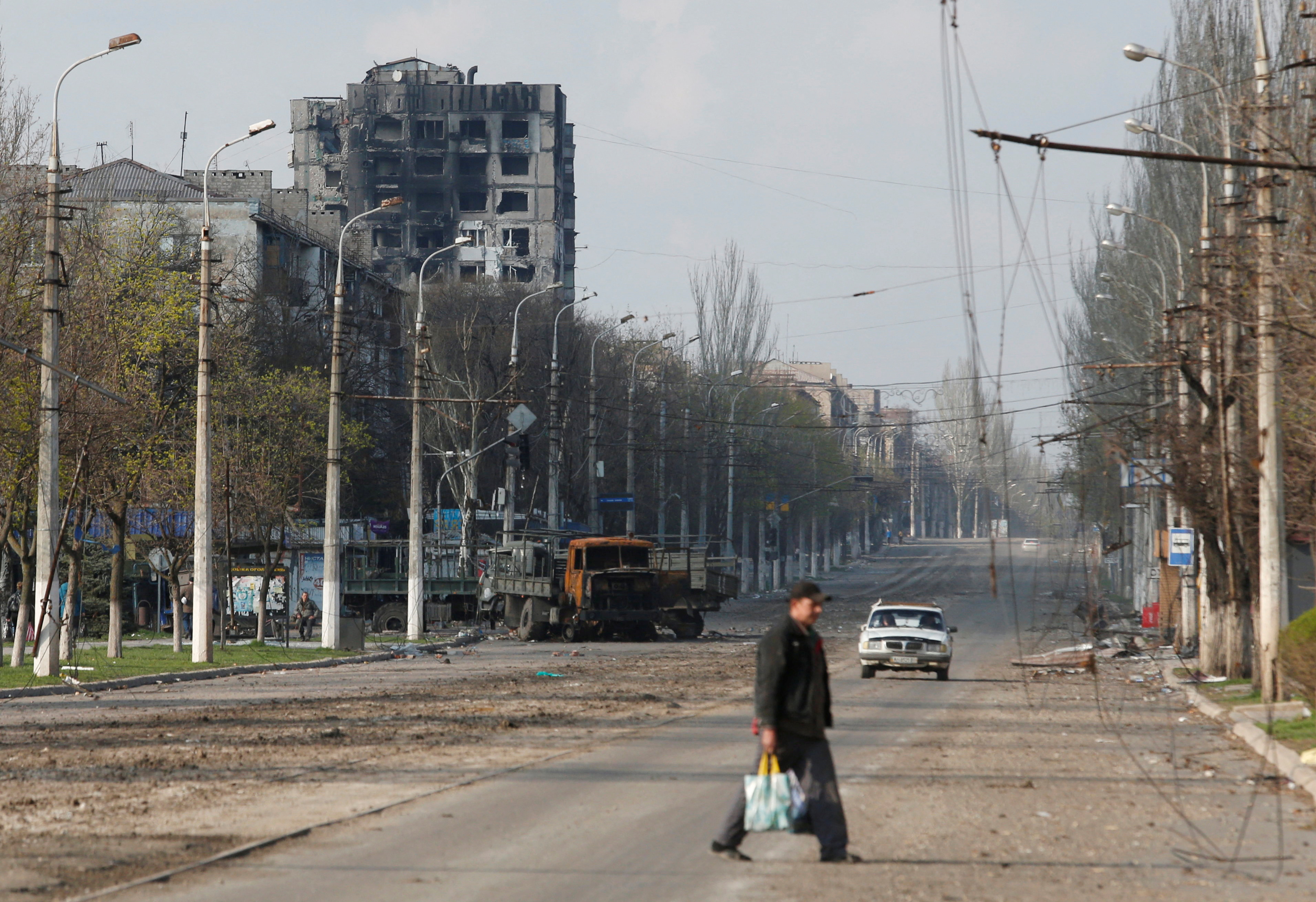 A local crosses a street damaged during the Ukraine-Russia conflict on April 15, 2022 in the southern Ukrainian port city of Mariupol.  REUTERS / Alexander Ermochenko