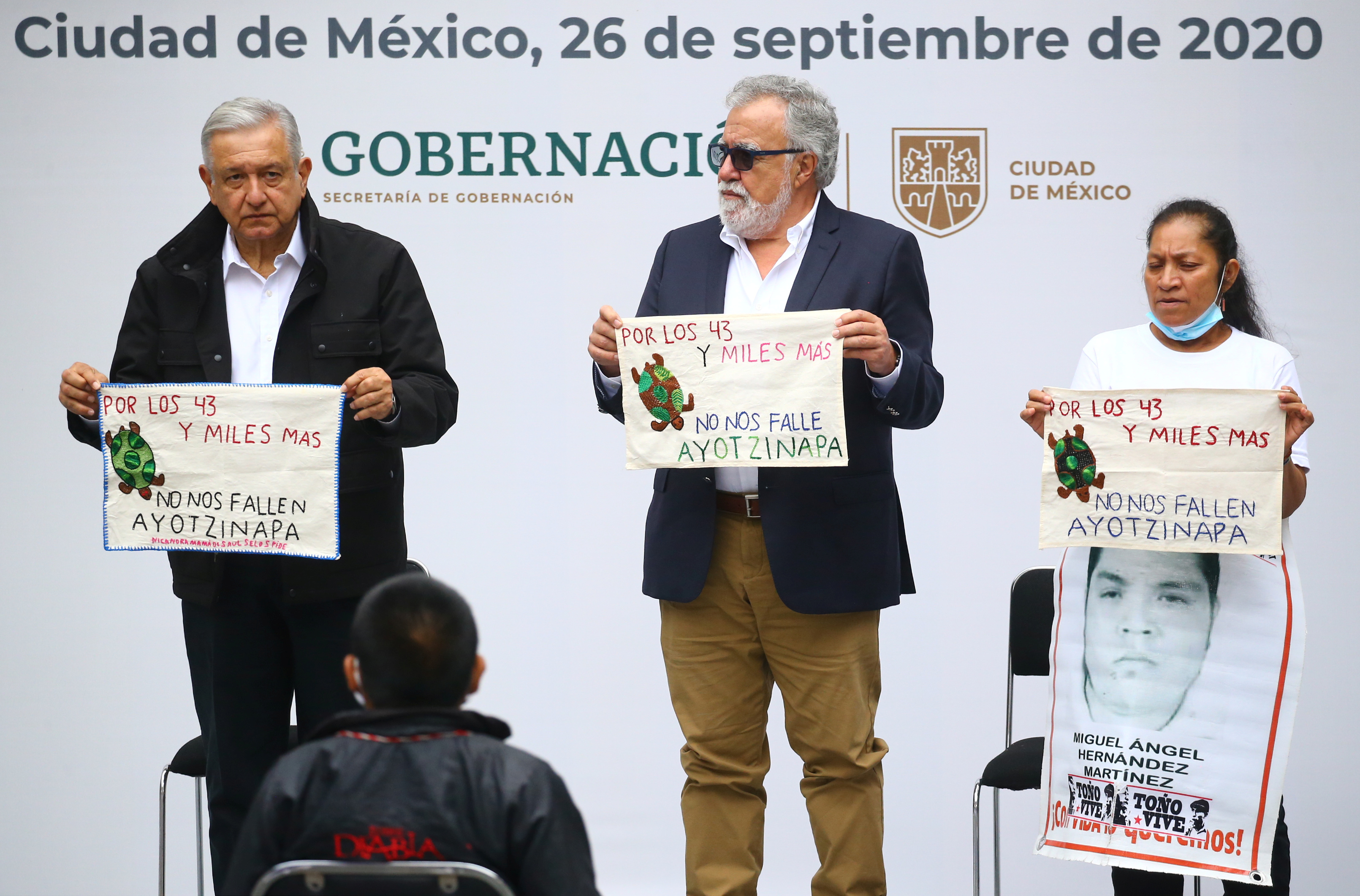 El presidente de México, Andrés Manuel López Obrador, el subsecretario de Derechos Humanos de México, Alejandro Encinas y María Martínez, madre de Miguel Ángel Hernández Martínez, sostienen piezas de tela bordadas por familiares de los 43 estudiantes desaparecidos de la Escuela de Formación de Maestros de Ayotzinapa, mientras asisten a la entrega un informe de investigación con motivo del sexto aniversario de su desaparición, en el Palacio Nacional en la Ciudad de México, México el 26 de septiembre de 2020.