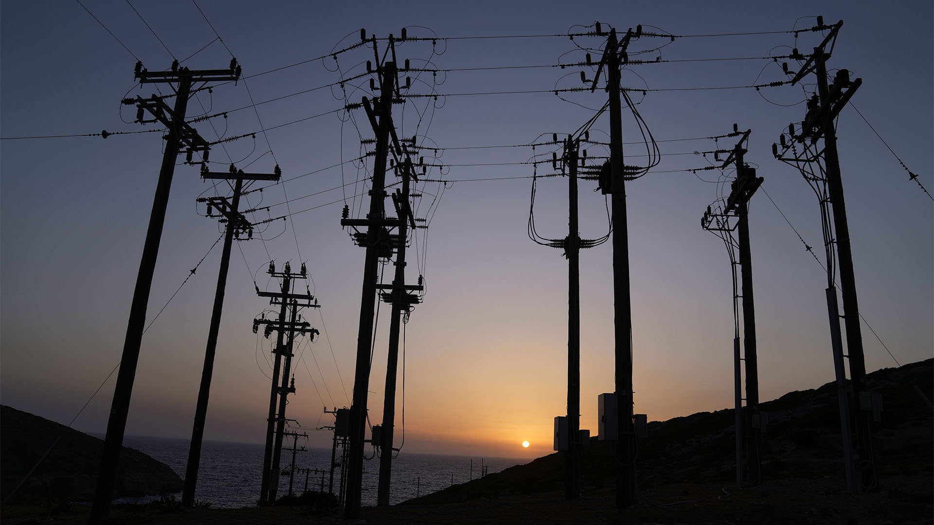 The sun sets behind power poles on the island of Tilos (AP Photo/Thanassis Stavrakis)