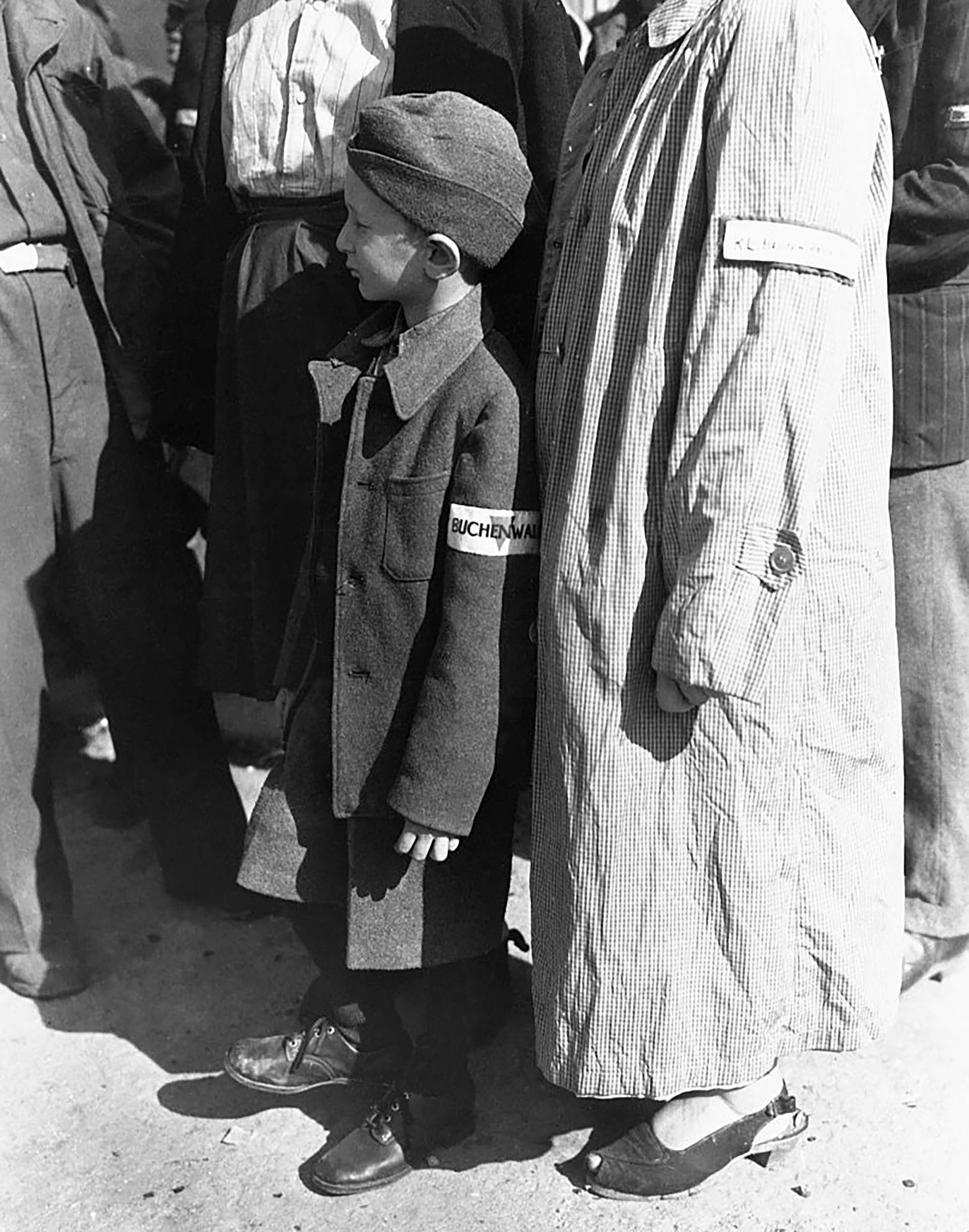 Un huérfano de guerra de seis años, con una insignia de Buchenwald en la manga, espera que lo llamen durante el pase de lista en el campamento de Buchenwald, Alemania, para partir hacia una nueva vida en Suiza al final de la Segunda Guerra Mundial (Corbis vía Getty Images)
