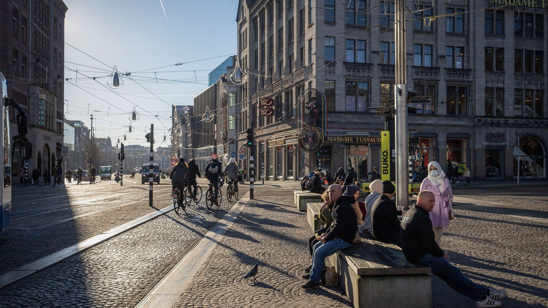Cyclists ride past travelers waiting for the tram during the introduction of lockdown measures in Amsterdam, Netherlands, on Tuesday, Dec. 21, 2021. The Dutch government has enforced a stricter lockdown to stem a surge in coronavirus infections caused by the spread of the omicron variant. Photographer: Peter Boer/Bloomberg