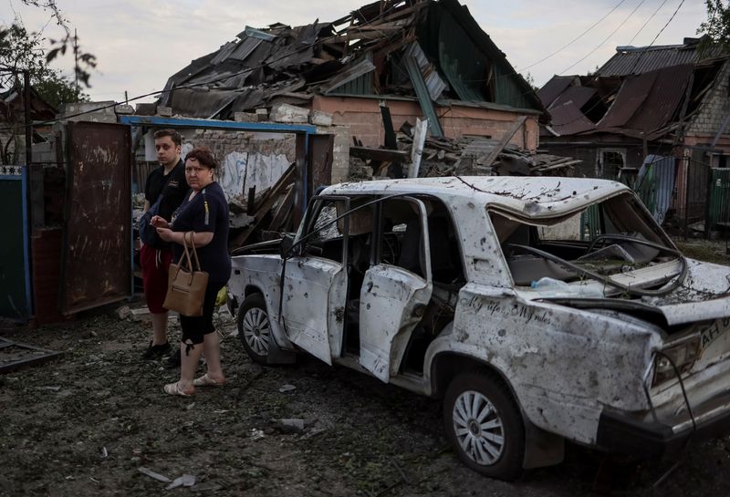 Residentes locales se paran cerca de un edificio destruido por el ataque de misiles rusos, en medio de la invasión de Rusia a Ucrania, en la ciudad de Pokrovsk, en la región de Donetsk, Ucrania. 15 de junio de 2022. REUTERS/Gleb Garanich