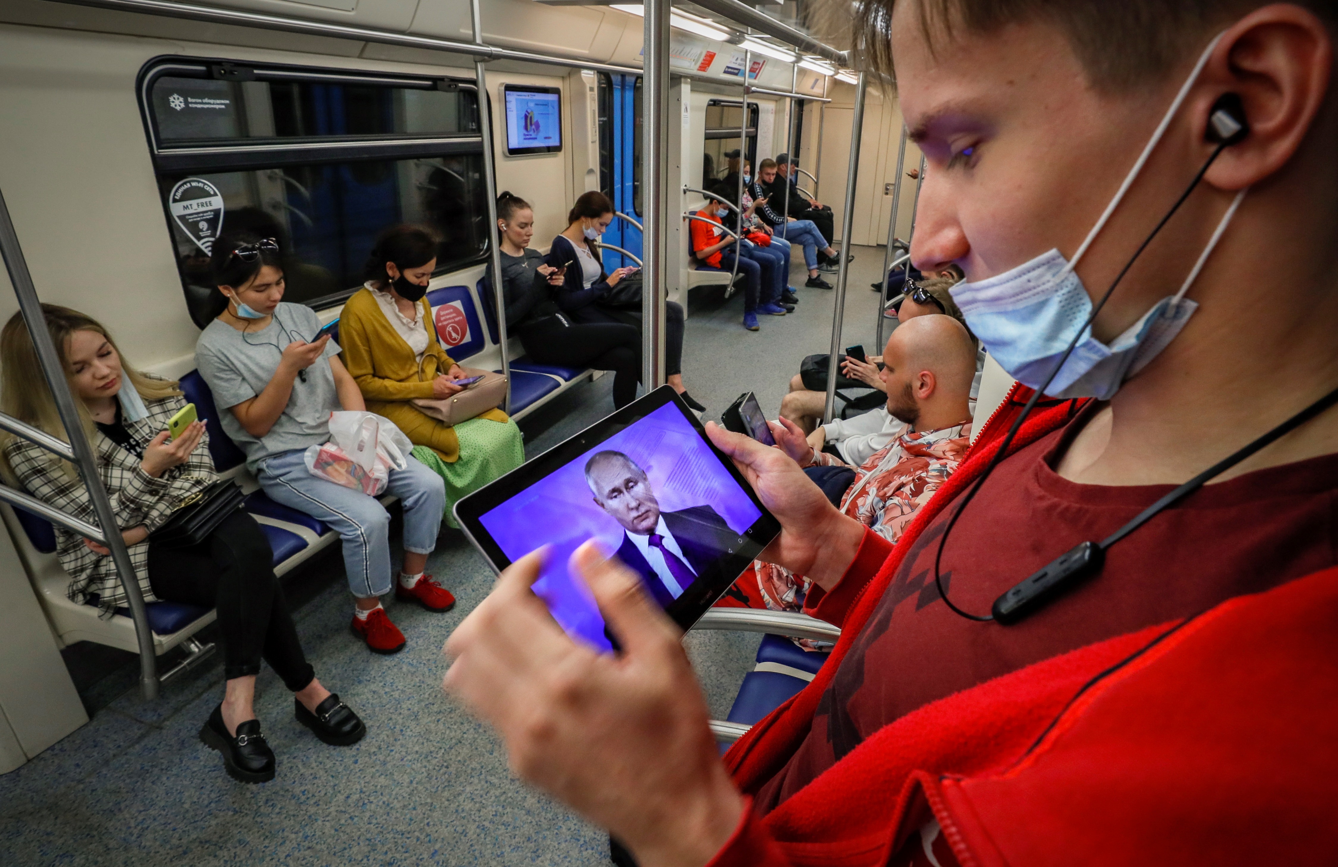 Pasajeros del metro de Moscú observando sus dispositivos móviles sin utilizar mascarillas o llevándolas en la barbilla. Expresan una enorme desconfianza en las autoridades. EFE/ Yuri Kochetkov