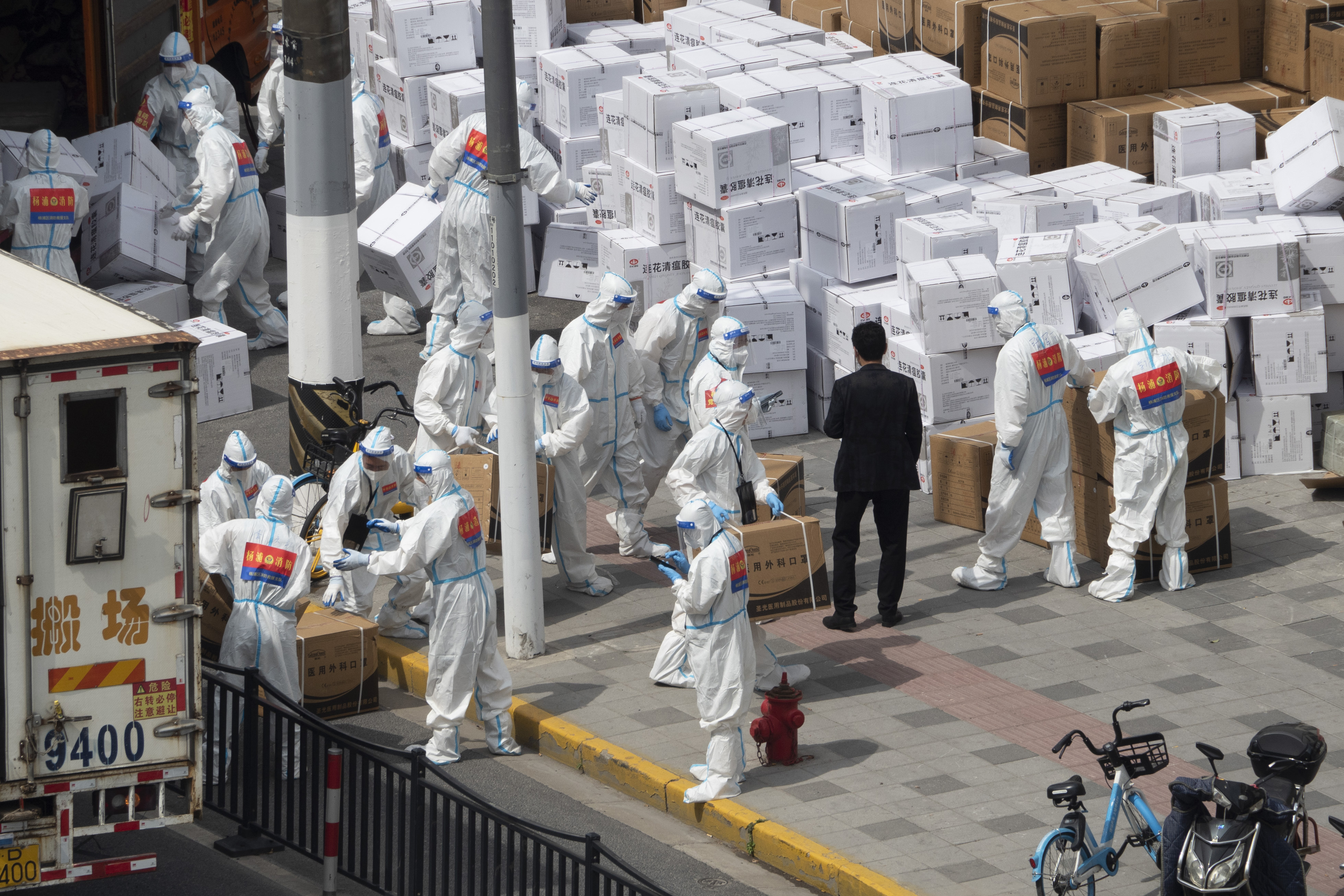Los trabajadores descargan suministros, incluidas cajas de máscaras, en Shanghái el domingo 10 de abril de 2022. (Chinatopix via AP)