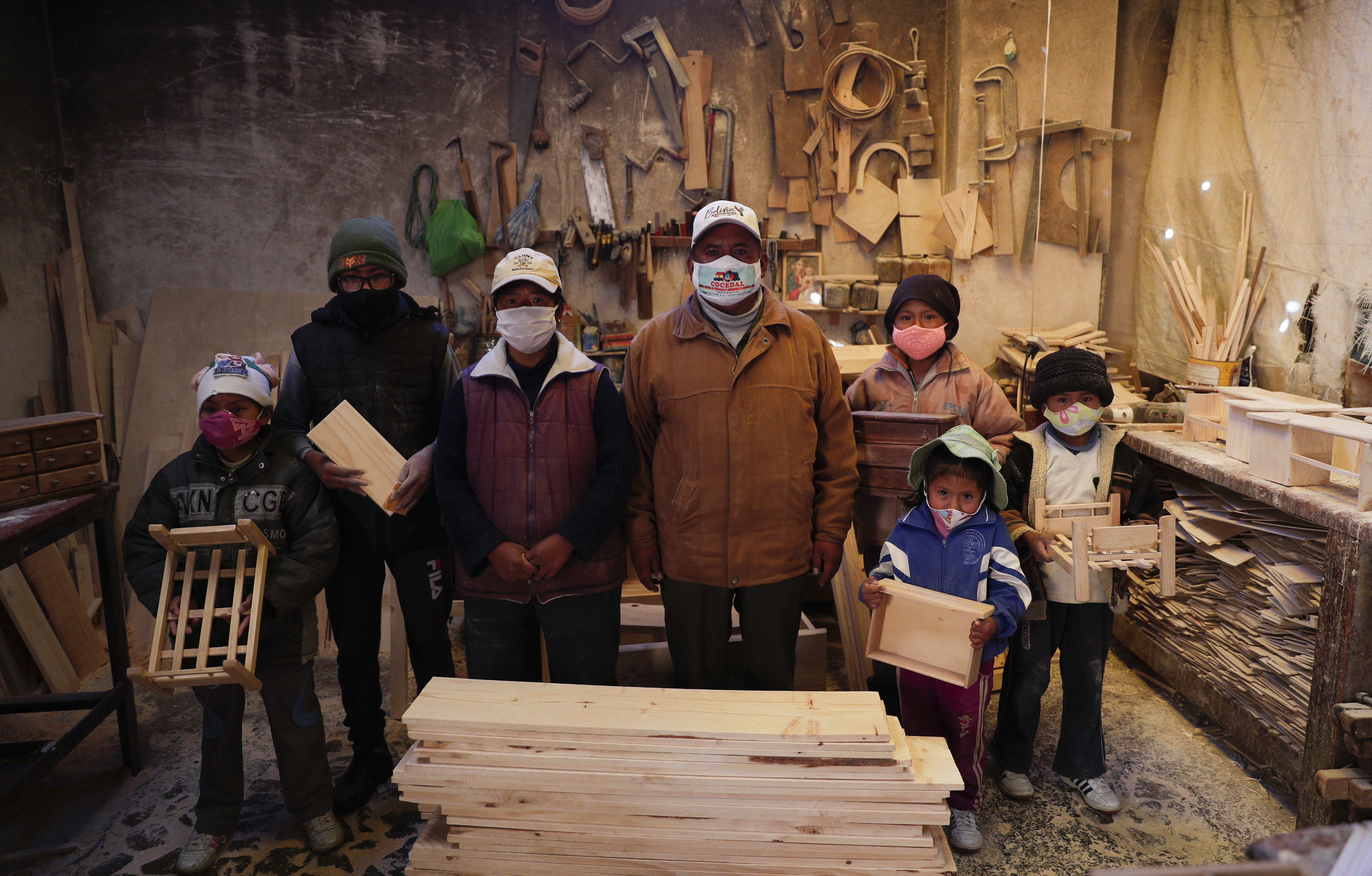 En El Alto, un suburbio ubicado en una parte elevada de La Paz, Bolivia, cinco hermanos de entre 6 y 14 años de edad se envuelven en abrigos y sombreros contra el aire frío de la montaña mientras ellos y sus padres trabajan en el pequeño taller de carpintería familiar.