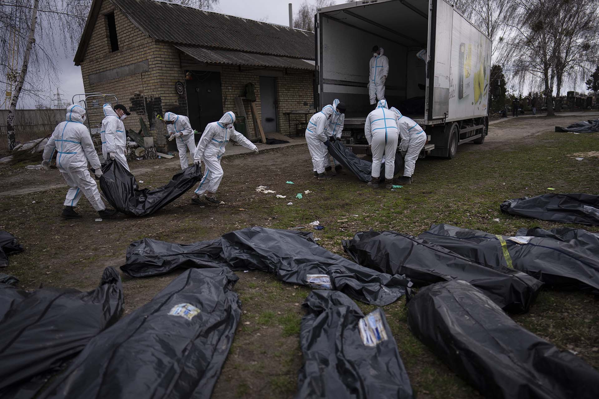 Voluntarios cargan en un camión los cadáveres de los civiles asesinados en Bucha para llevarlos a un depósito para su investigación, en las afueras de Kiev (AP Photo/Rodrigo Abd)