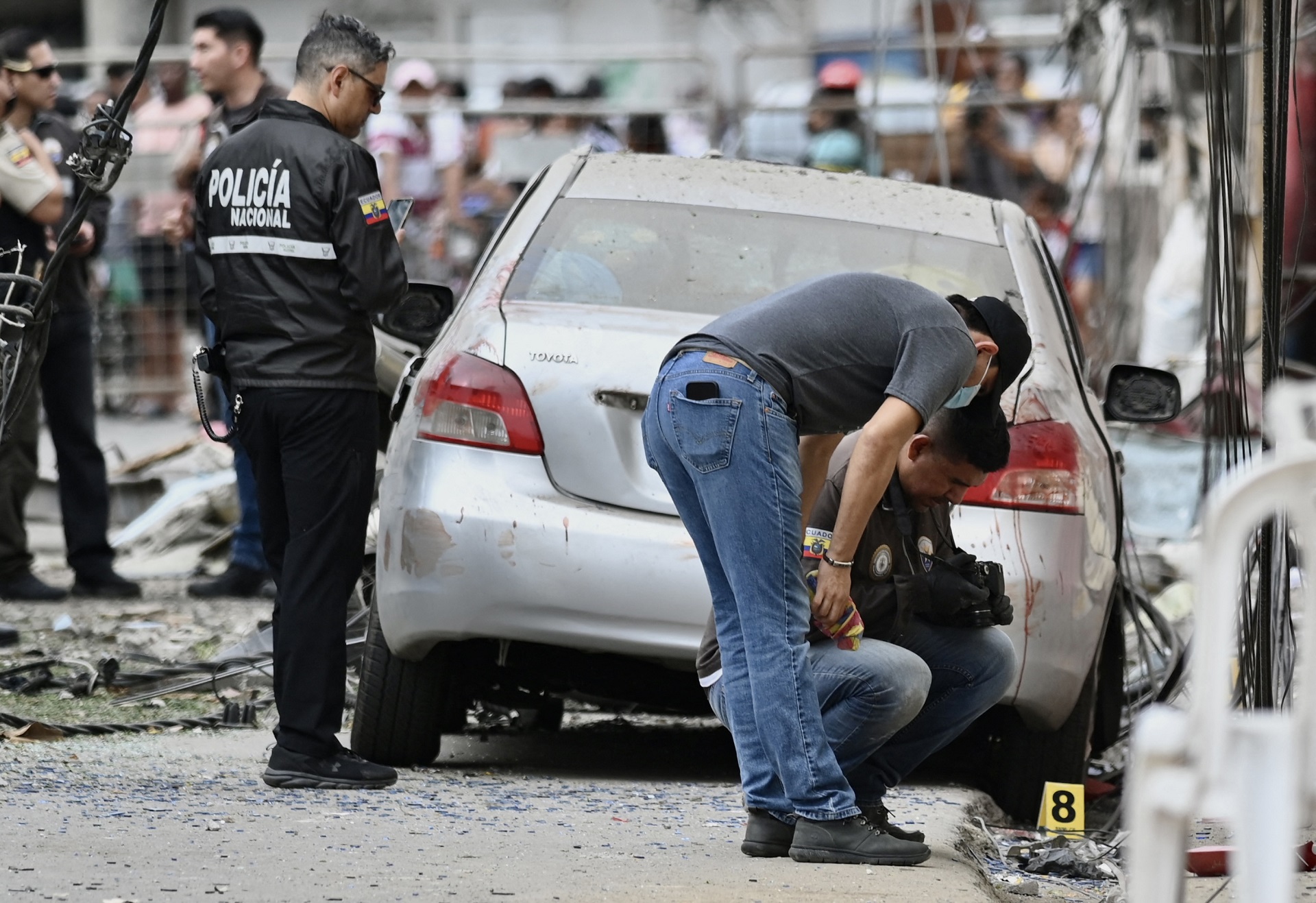 Miembros de la Policía Nacional inspeccionan el lugar de una explosión, que el gobierno ecuatoriano atribuye al crimen organizado, en el sur de Guayaquil, Ecuador, el 14 de agosto de 2022 (AFP)
