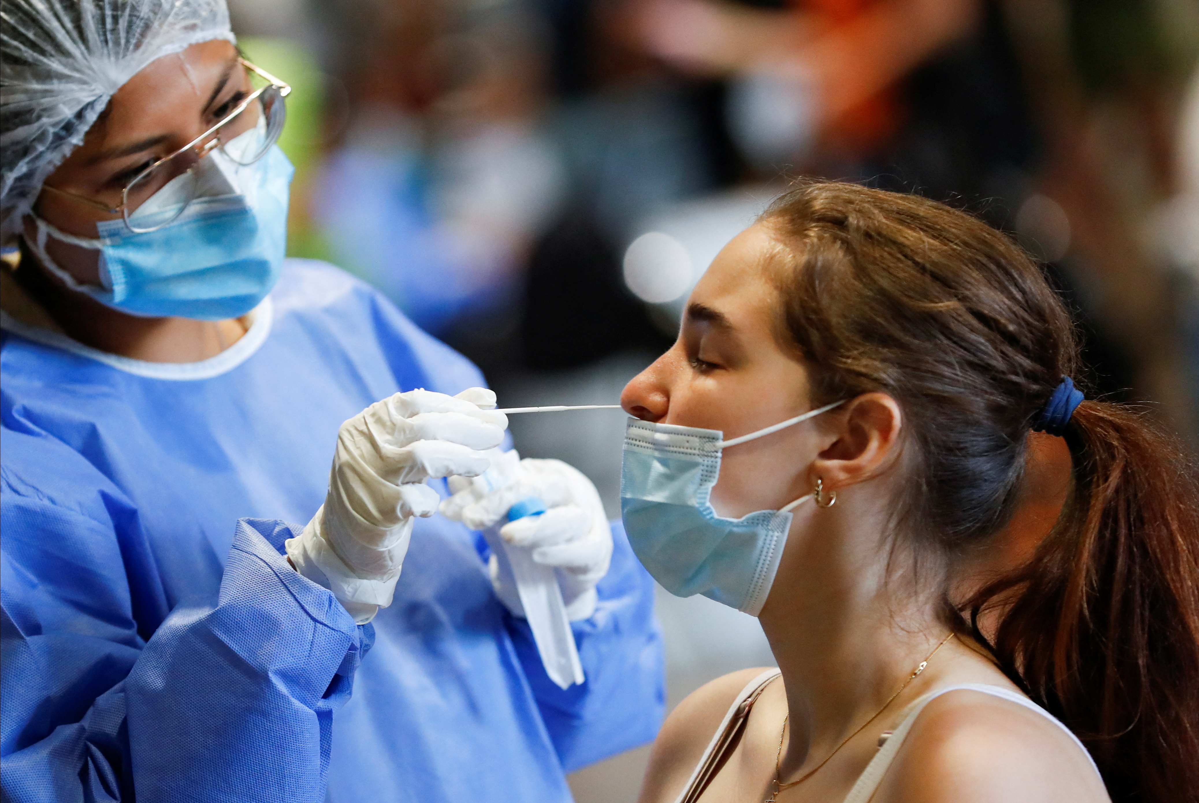 A healthcare worker takes a swab sample from a woman to be tested for the coronavirus disease (COVID-19), at La Rural, in Buenos Aires, Argentina December 23, 2021. Picture taken December 23, 2021. REUTERS/Agustin Marcarian