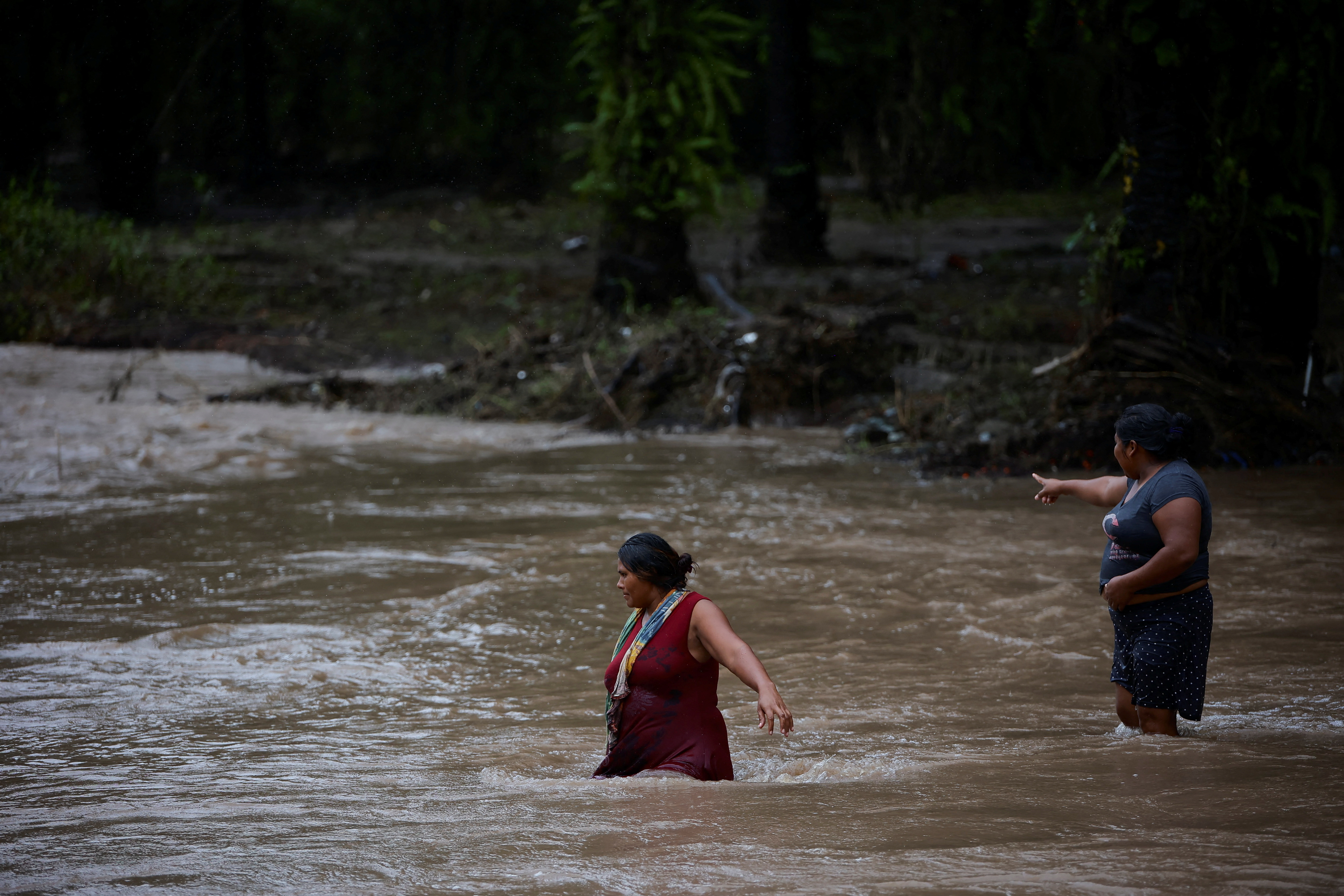 Mujeres caminan por una zona inundada tras el impacto de la tormenta tropical Julia, en Progreso, Honduras (REUTERS/Yoseph Amaya)