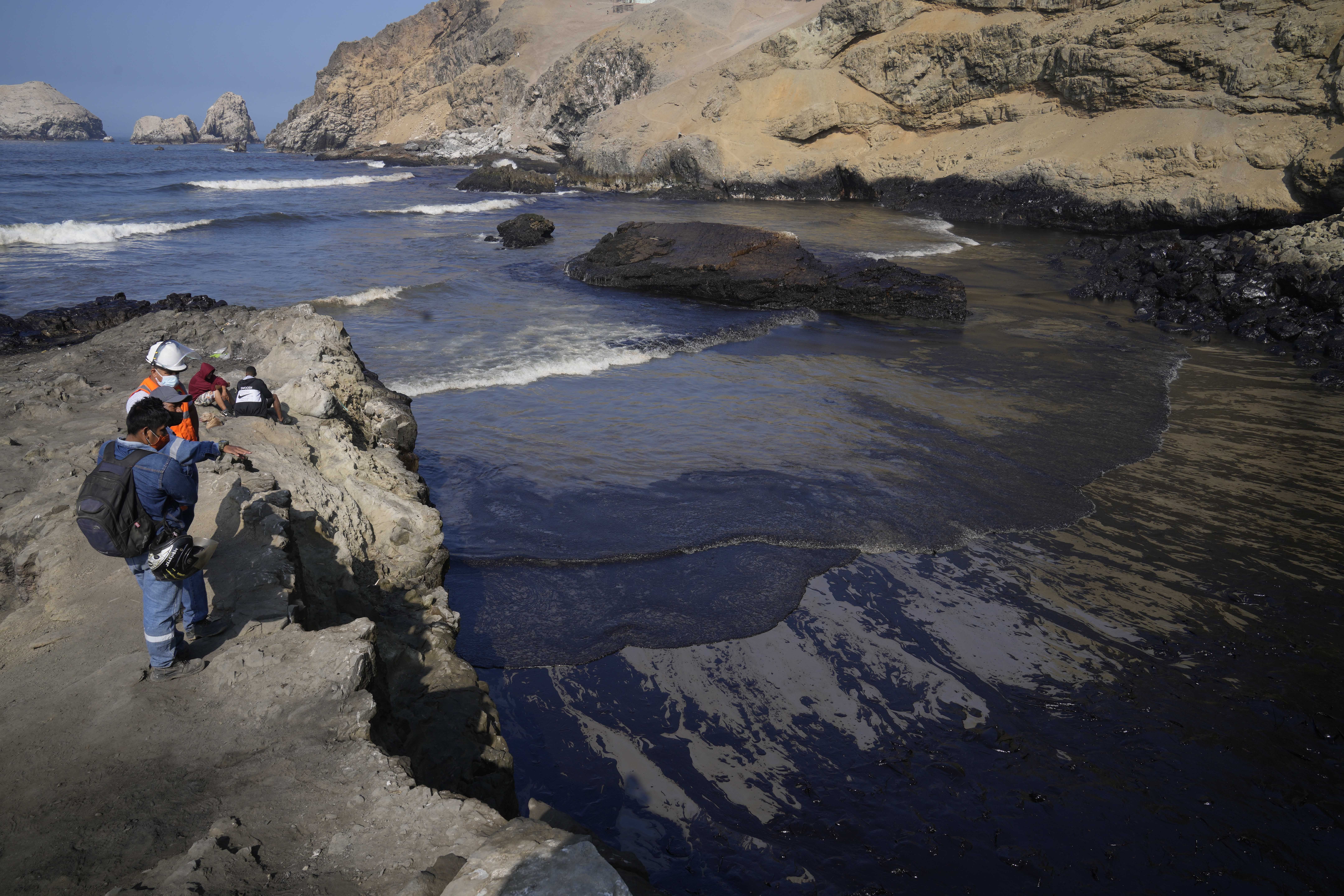 Los trabajadores observan el petróleo en las aguas de la playa Cavero en Ventanilla, Callao, Perú. (AP Photo/Martin Mejia)