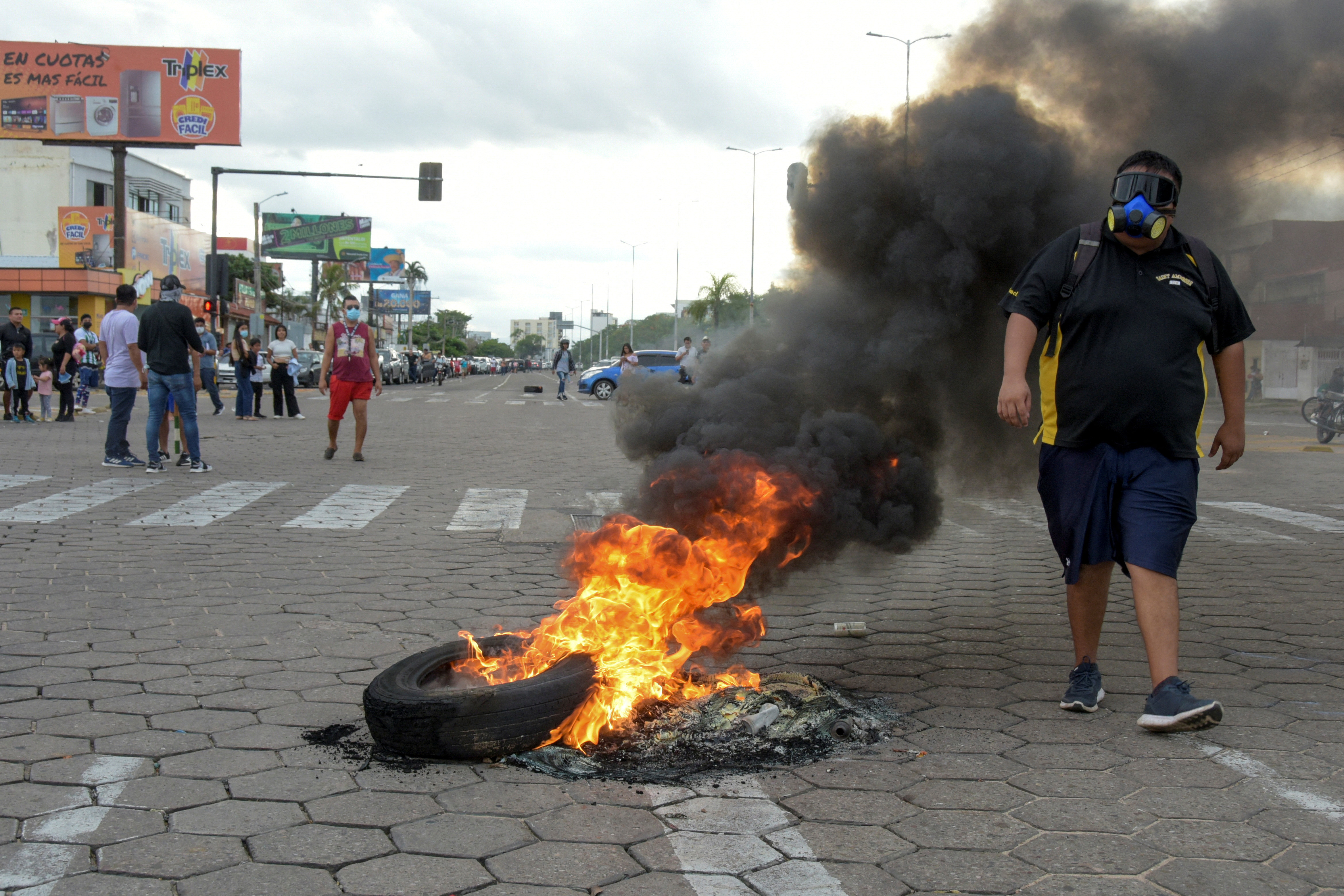 Un sostenitore di Luis Fernando Camacho passa davanti a una barricata in fiamme durante una protesta dopo essere stato arrestato dalla polizia boliviana a Santa Cruz de la Sierra il 28 dicembre 2022 (REUTERS/Andrea Martinez)
