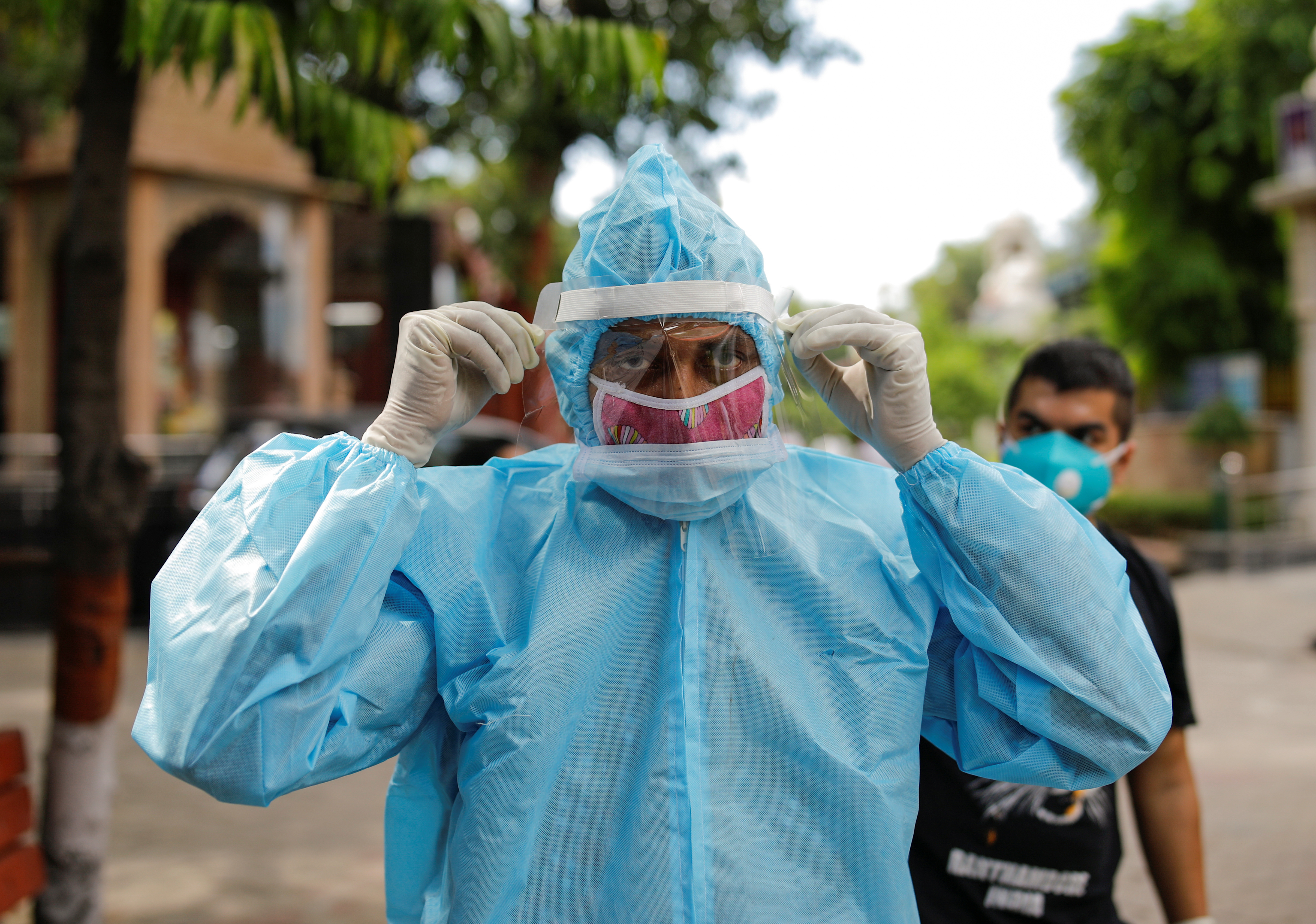 Un hombre que usa equipo de protección personal (PPE) ajusta su protector facial antes de la cremación de un familiar que murió debido a la enfermedad coronavirus (COVID-19), en un crematorio en Nueva Delhi, India, el 22 de agosto de 2020. REUTERS/Adnan Abidi