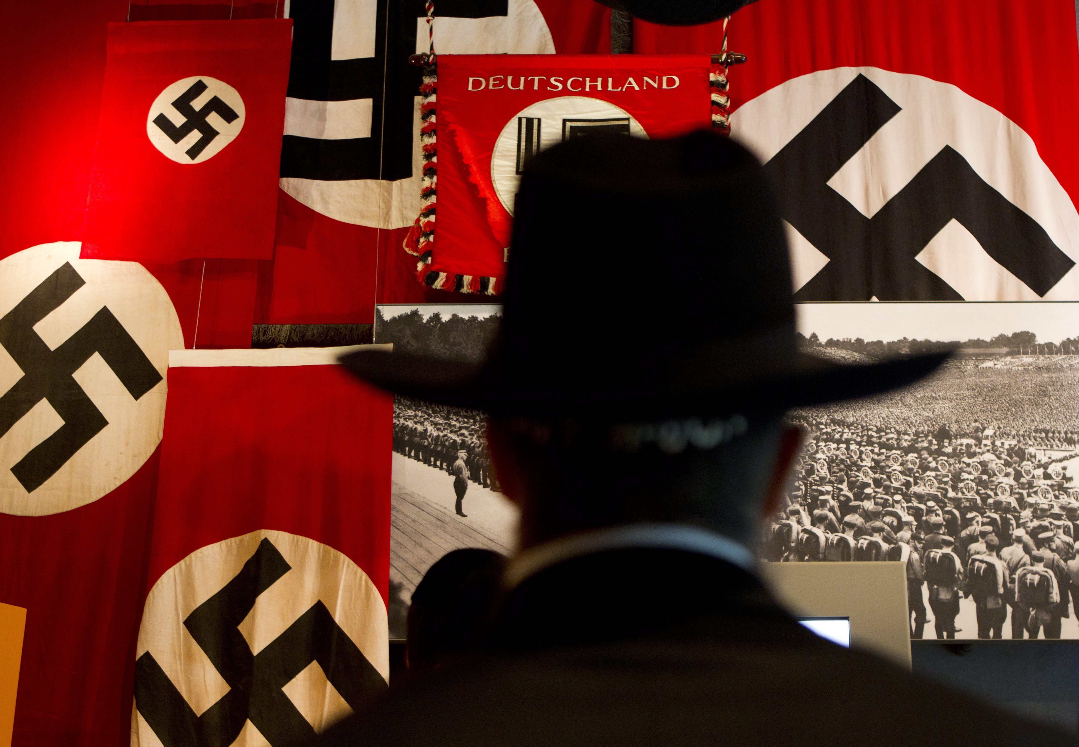 Un judío ultraortodoxo observa fotografías y banderas nazis con la esvástica durante una visita a un museo. EFE/JIM HOLLANDER/Archivo
