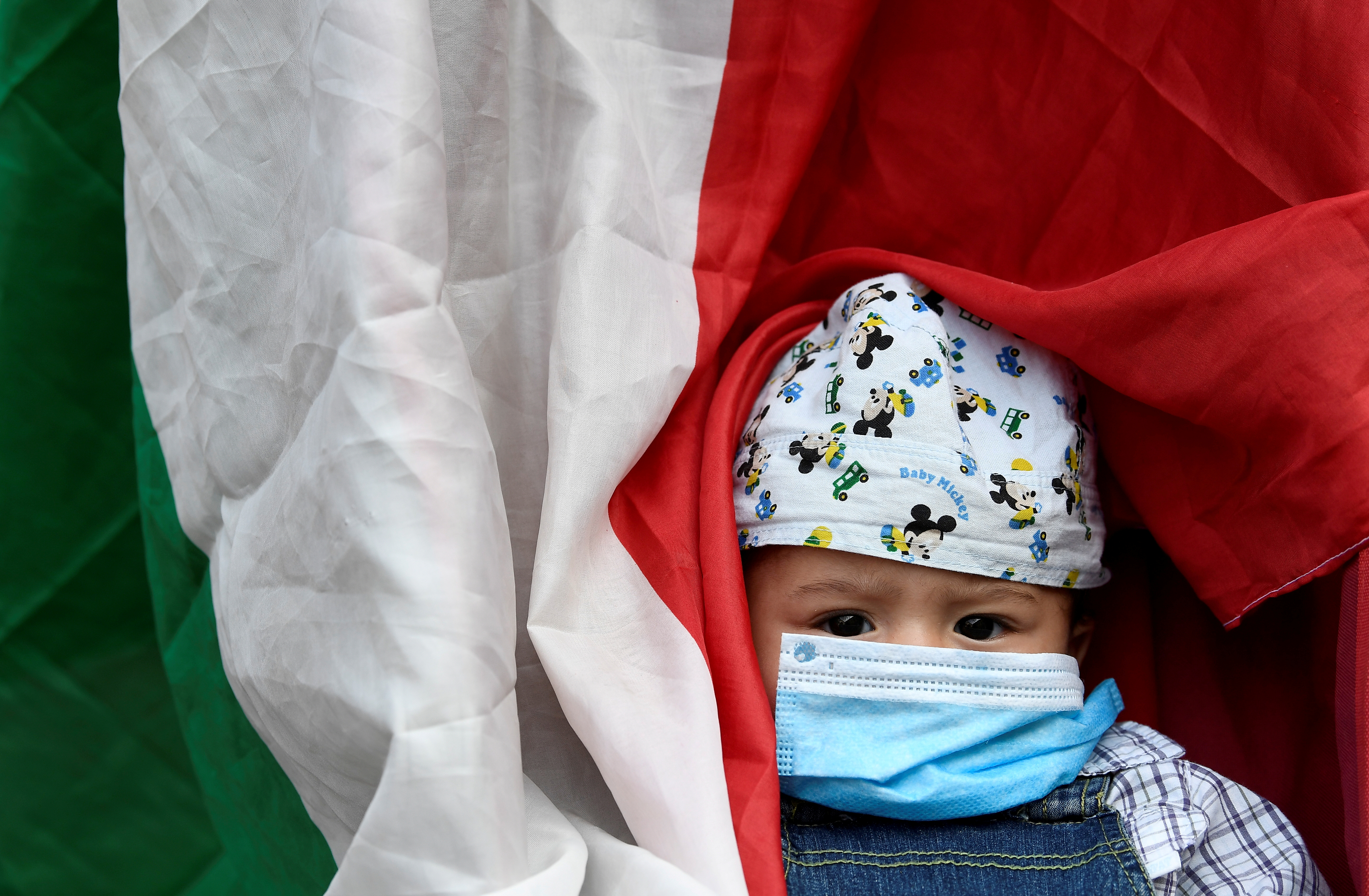 ARCHIVO FOTOGRÁFICO: Un niño con una máscara protectora es visto junto a la bandera italiana durante una protesta frente al ayuntamiento de Milán el 18 de mayo de 2020. REUTERS/Flavio Lo Scalzo