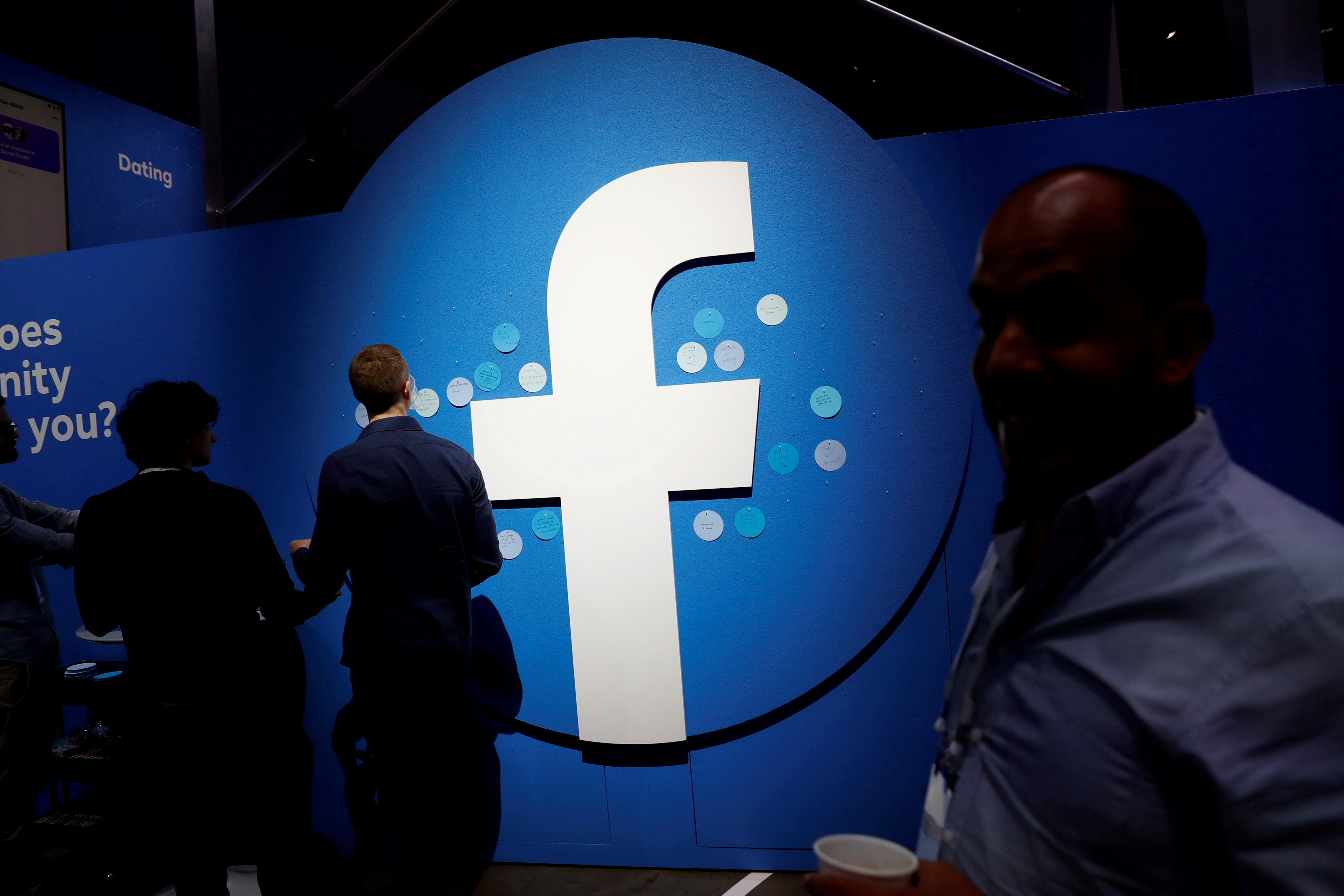FILE PHOTO: FILE PHOTO: Attendees walk past a Facebook logo during Facebook Inc's F8 developers conference in San Jose, California, U.S., April 30, 2019.  REUTERS/Stephen Lam/File Photo  GLOBAL BUSINESS WEEK AHEAD/File Photo
