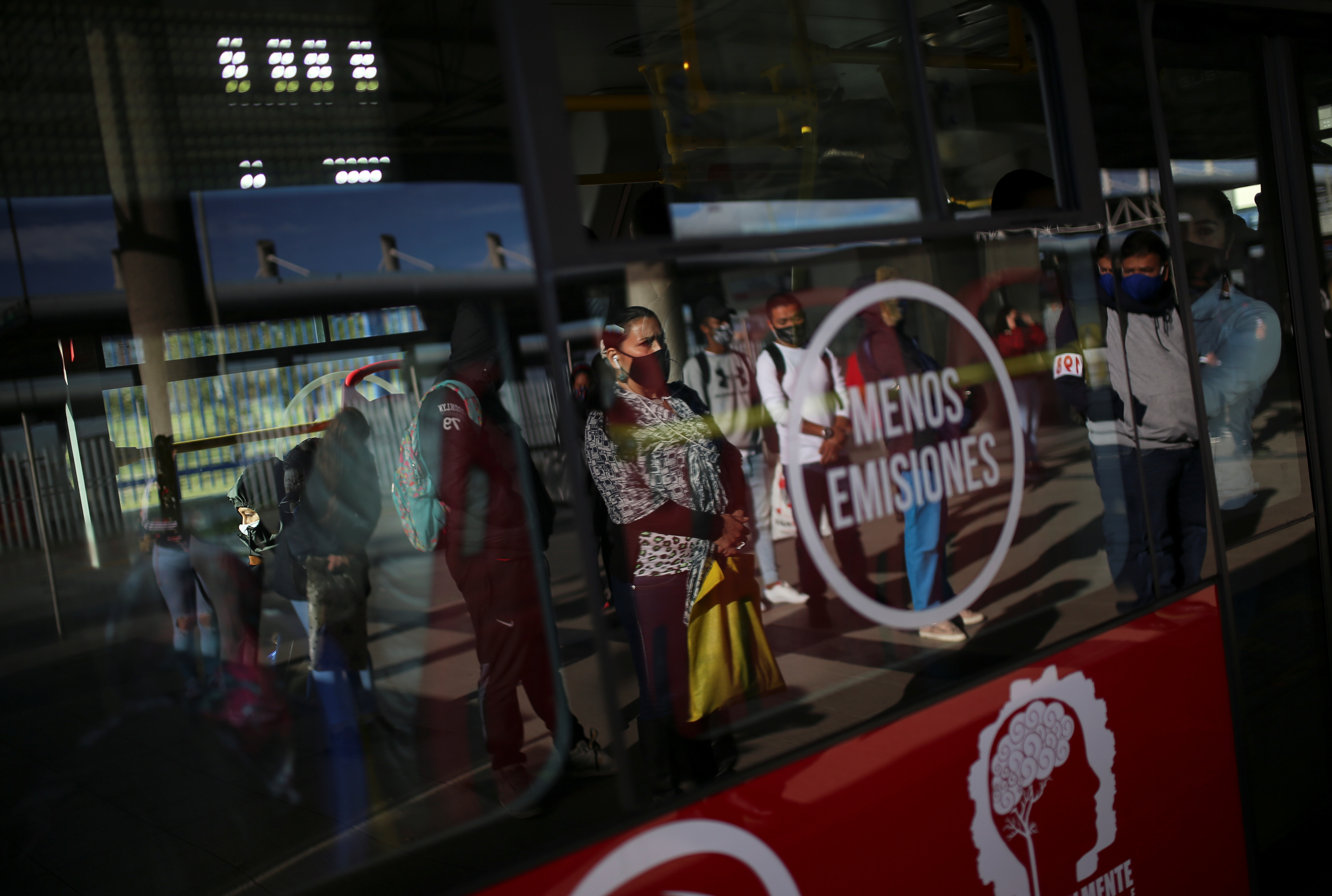 People wearing protective masks due to the ongoing coronavirus disease (COVID-19) outbreak, are seen reflected in a bus window at a station of the TransMilenio public transport system after the mayor's office ended the quarantine in Bogota, Colombia August 27, 2020. REUTERS/Luisa Gonzalez