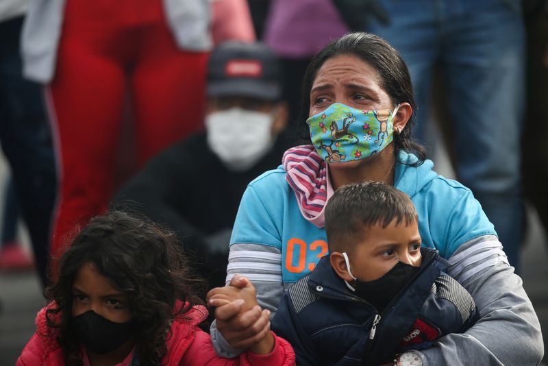 Foto de archivo. Una mujer migrante venezolana con mascarilla sostiene a un niño mientras participa en una protesta contra el bloqueo de los autobuses que los migrantes contrataron para llegar a la frontera entre Colombia y Venezuela, en medio de la pandemia del COVID-19 en Bogotá, Colombia, 29 de abril, 2020. REUTERS/Luisa González