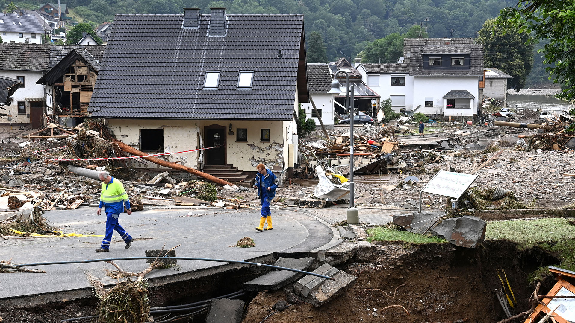 Dos hombres caminan por una carretera que se deslizó parcialmente después de que las inundaciones causaron daños importantes en Schuld, cerca de Bad Neuenahr-Ahrweiler, en el oeste de Alemania