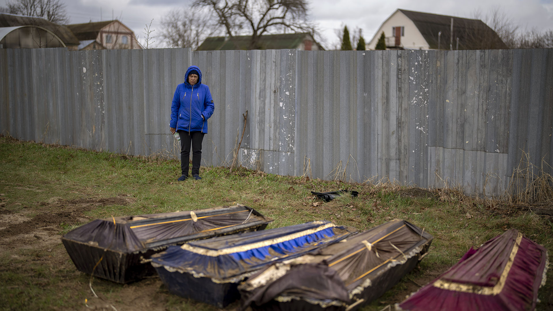 Ira Slepchenko, de 54 años, de pie junto a ataúdes, uno de ellos con el cuerpo de su esposo Sasha Nedolezhko, de 43 años, durante una exhumación de una fosa común en Mykulychi, Ucrania. (AP Foto/Emilio Morenatti) 