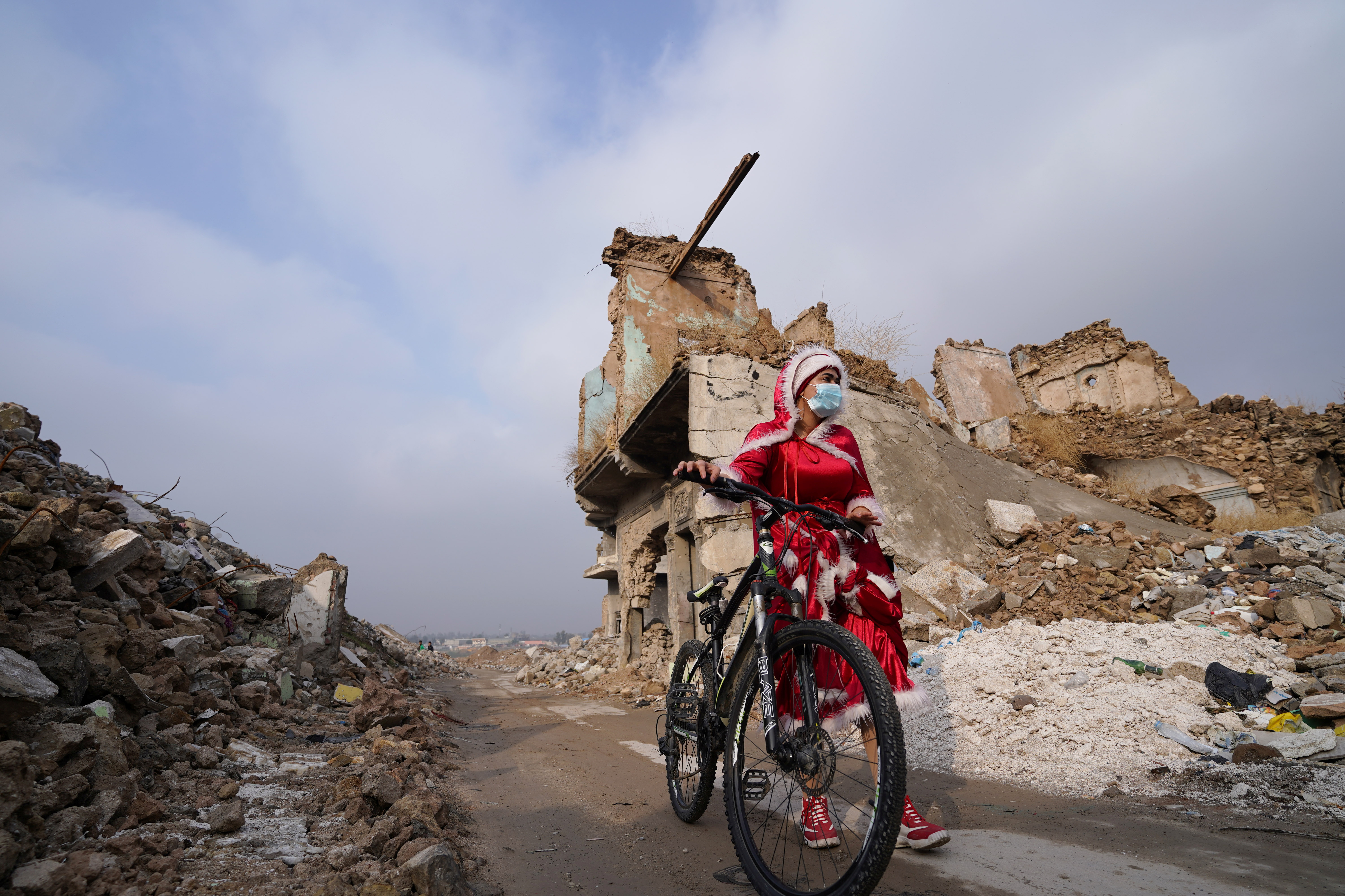 Una mujer iraquí, vestida de Papá Noel, camina con una bicicleta en la antigua ciudad de Mosul, Irak  (REUTERS/Abdullah Rashid)