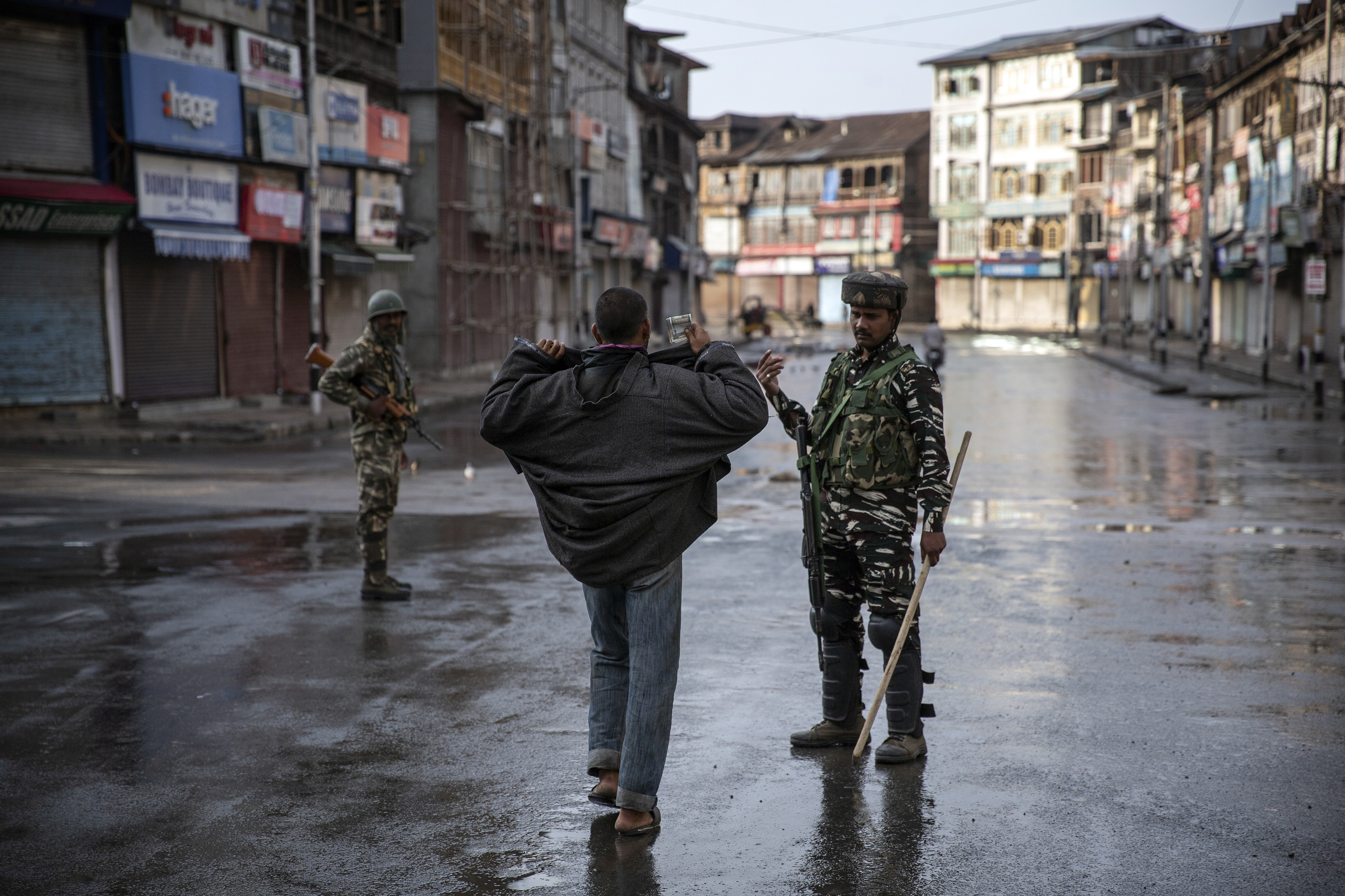 Un soldado paramilitar indio le ordena a un cachemir abrir su chaqueta antes de registrarlo durante el toque de queda en Srinagar, Cachemira controlada por los indios, el 8 de agosto de 2019. El hermoso valle del Himalaya está inundado de soldados y barricadas de alambre de púas. (Foto AP / Dar Yasin)