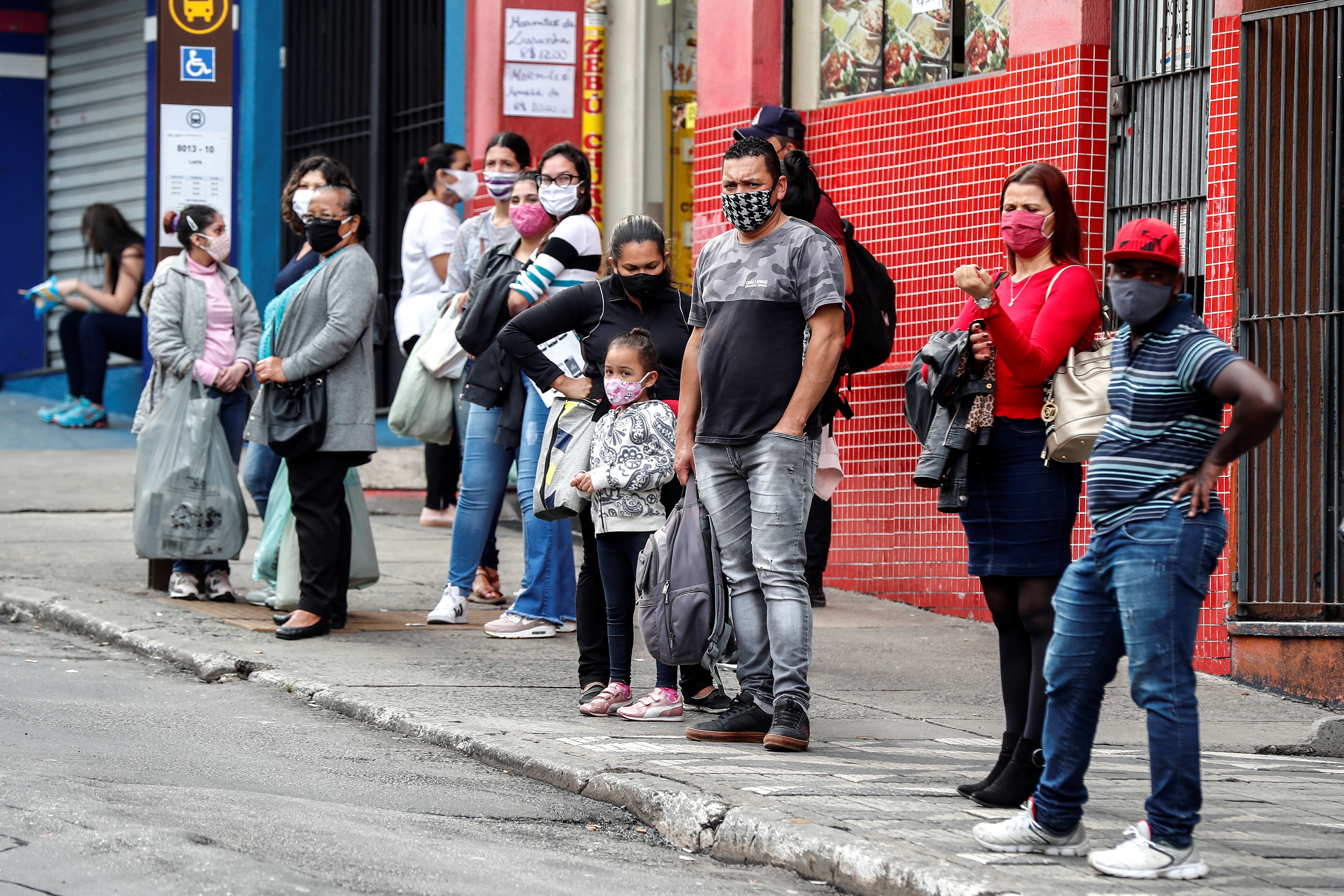 Personas con tapabocas esperan este jueves para tomar un bus de transporte público en Sao Paulo (Brasil). EFE/Sebastião Moreira
