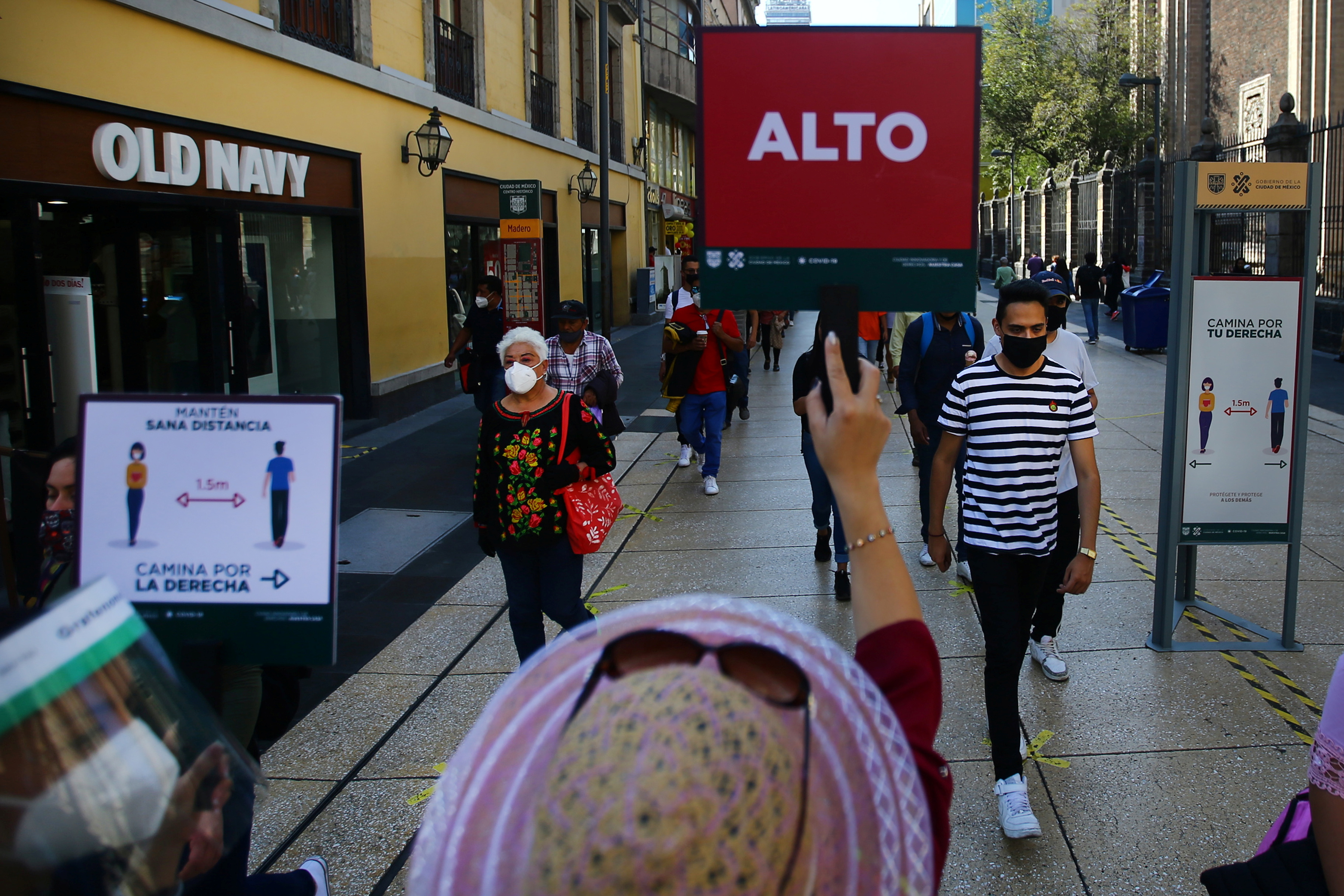 An employee holds a sign that reads " Stop" to organize people walking in downtown Mexico City as part of the measures during the spread of the coronavirus disease (COVID-19), Mexico November 13, 2020. REUTERS/Edgard Garrido