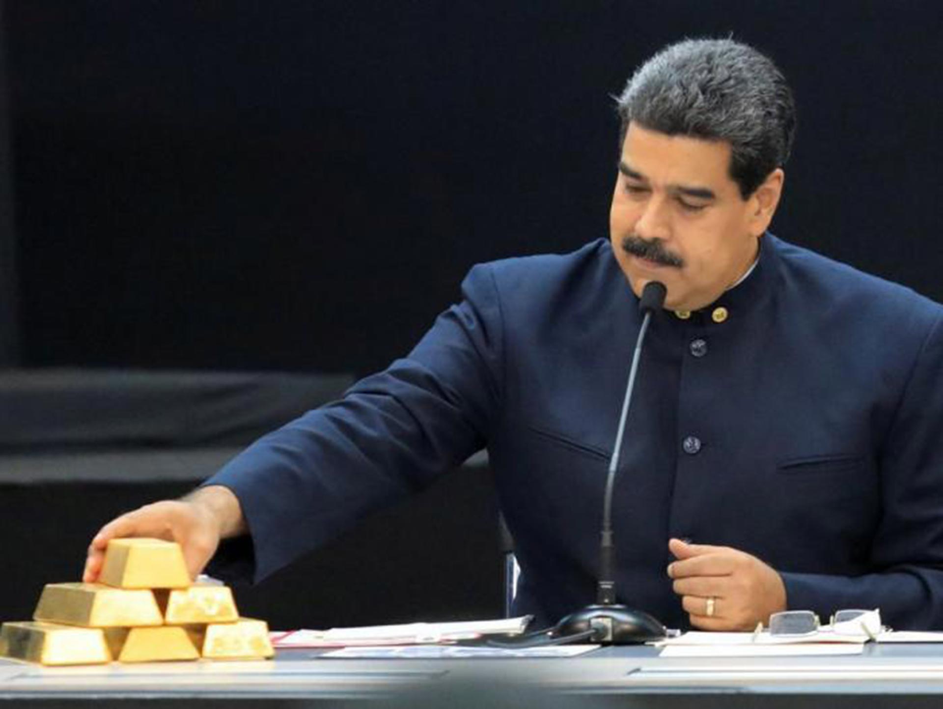 El dictador venezolano Nicolás Maduro junto a una pila de lingotes de oro. 