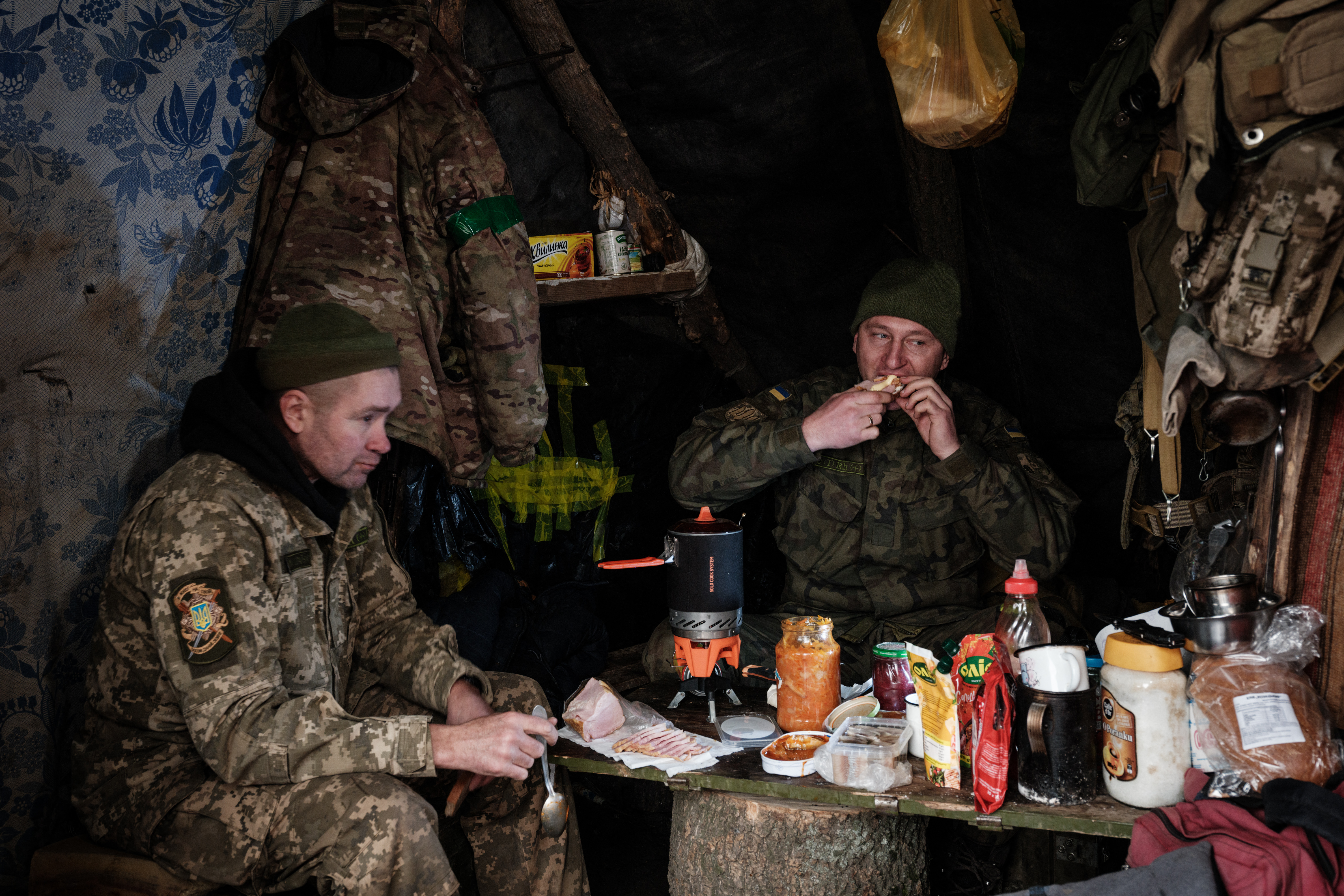 Los militares ucranianos comen en una choza en un lugar de retaguardia donde se corta madera para abastecer las posiciones de primera línea en la región de Donetsk (YASUYOSHI CHIBA / AFP)