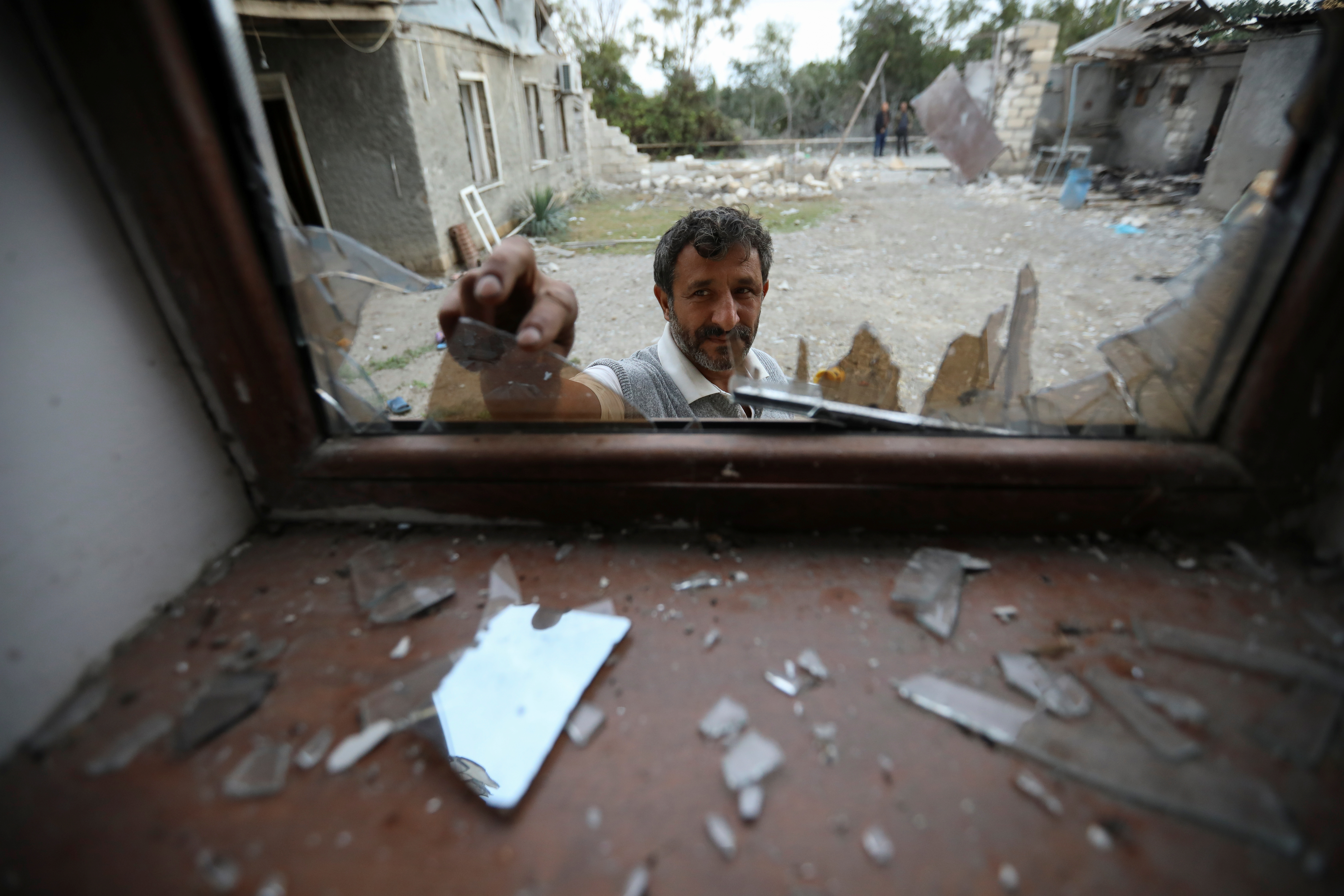 Un hombre quita vidrios rotos de una ventana en Garagoyunlu, Azerbaiyán (REUTERS/Aziz Karimov)
