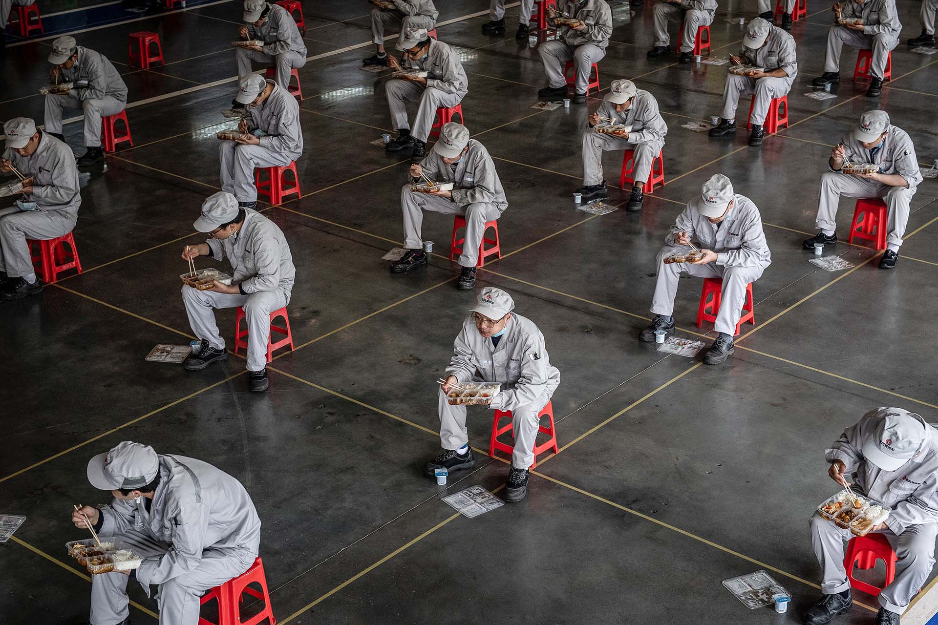 Empleados de una fábrica de Honda, en Wuhan, China, comparten su almuerzo manteniendo la distancia social, tras la reapertura de actividad fabril en la ciudad donde comenzó a expandirse el covid-19 (23 de marzo)