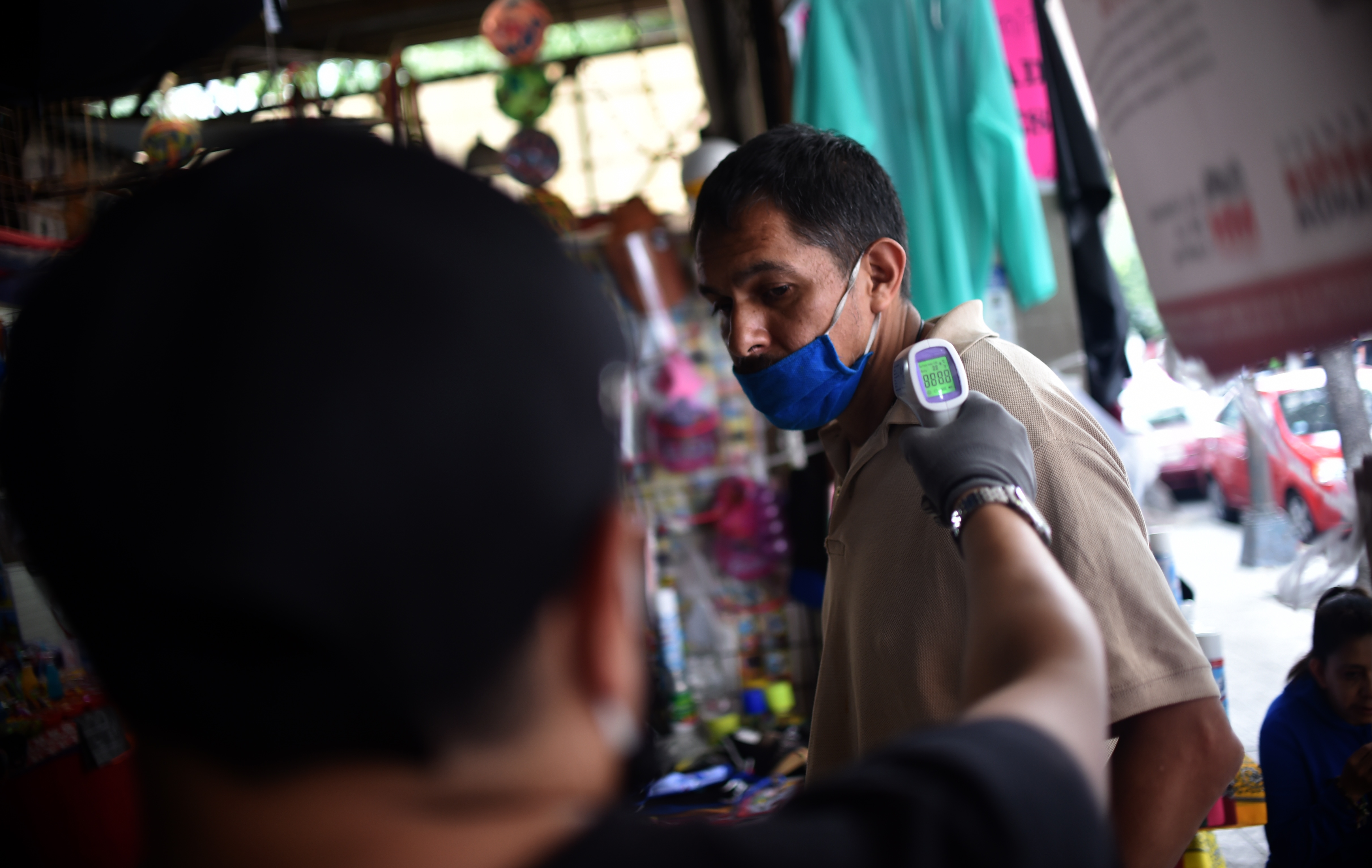 Un trabajador verifica la temperatura corporal de un cliente a la entrada de un mercado popular en la Ciudad de México el 29 de junio de 2020. (Foto: RODRIGO ARANGUA / AFP)
