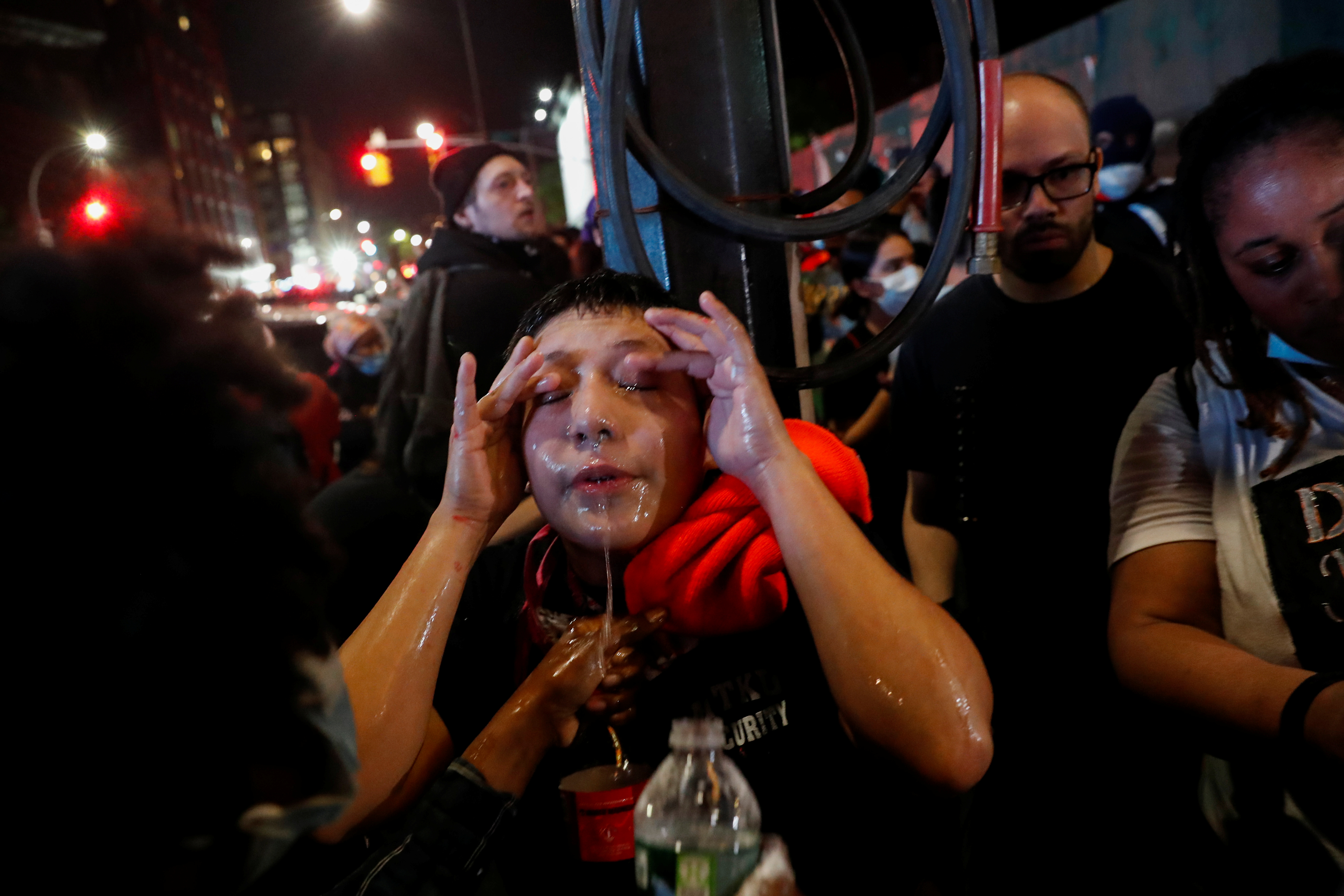 Una manifestante trata de reducir el efecto de los gases lacrimógenos con un lavado de cara en una manifestación que se realizó este viernes por la noche en Brooklyn, Nueva York (REUTERS/Shannon Stapleton)