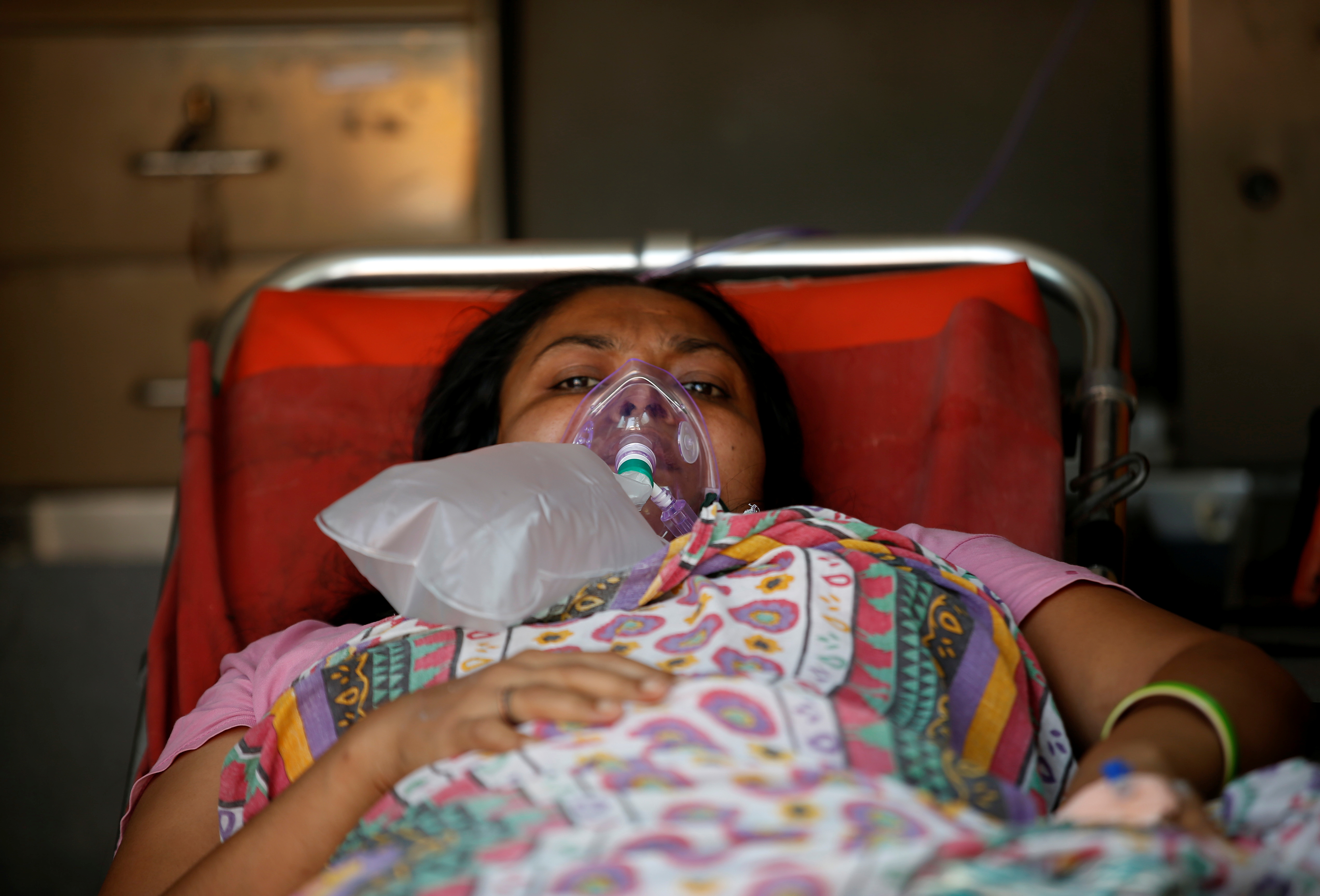 Una paciente con un problema respiratorio usa una máscara de oxígeno mientras yace dentro de una ambulancia esperando en una fila para ingresar a un hospital COVID-19, en medio de la pandemia de la enfermedad por coronavirus, Ahmedabad, India, 14 de abril de 2021. REUTERS / Amit Dave