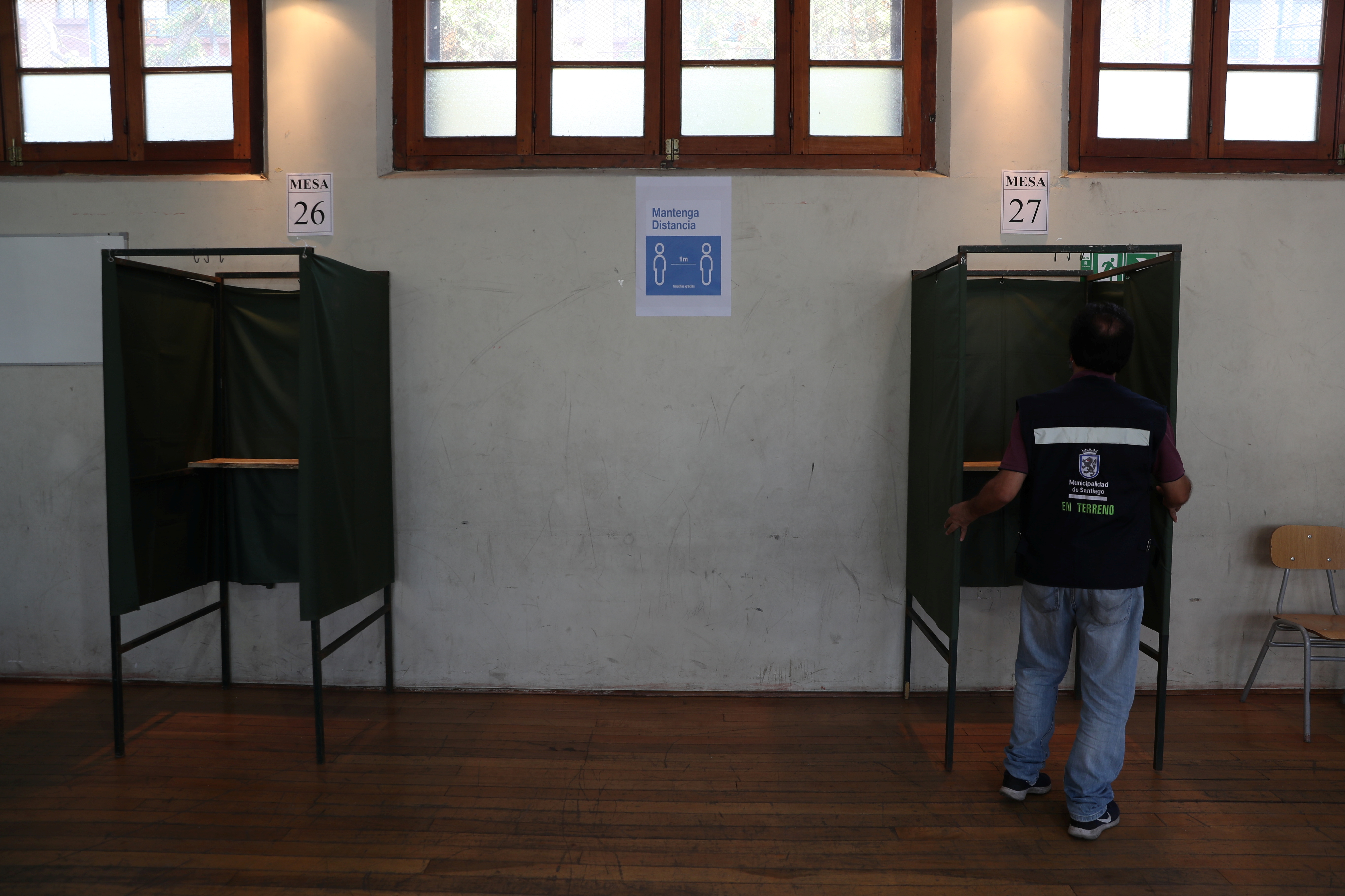 Un trabajador arregla una cabina de votación dentro de un colegio electoral durante un simulacro de votación antes del próximo referéndum sobre una nueva constitución chilena en Santiago, Chile, el 23 de octubre de 2020