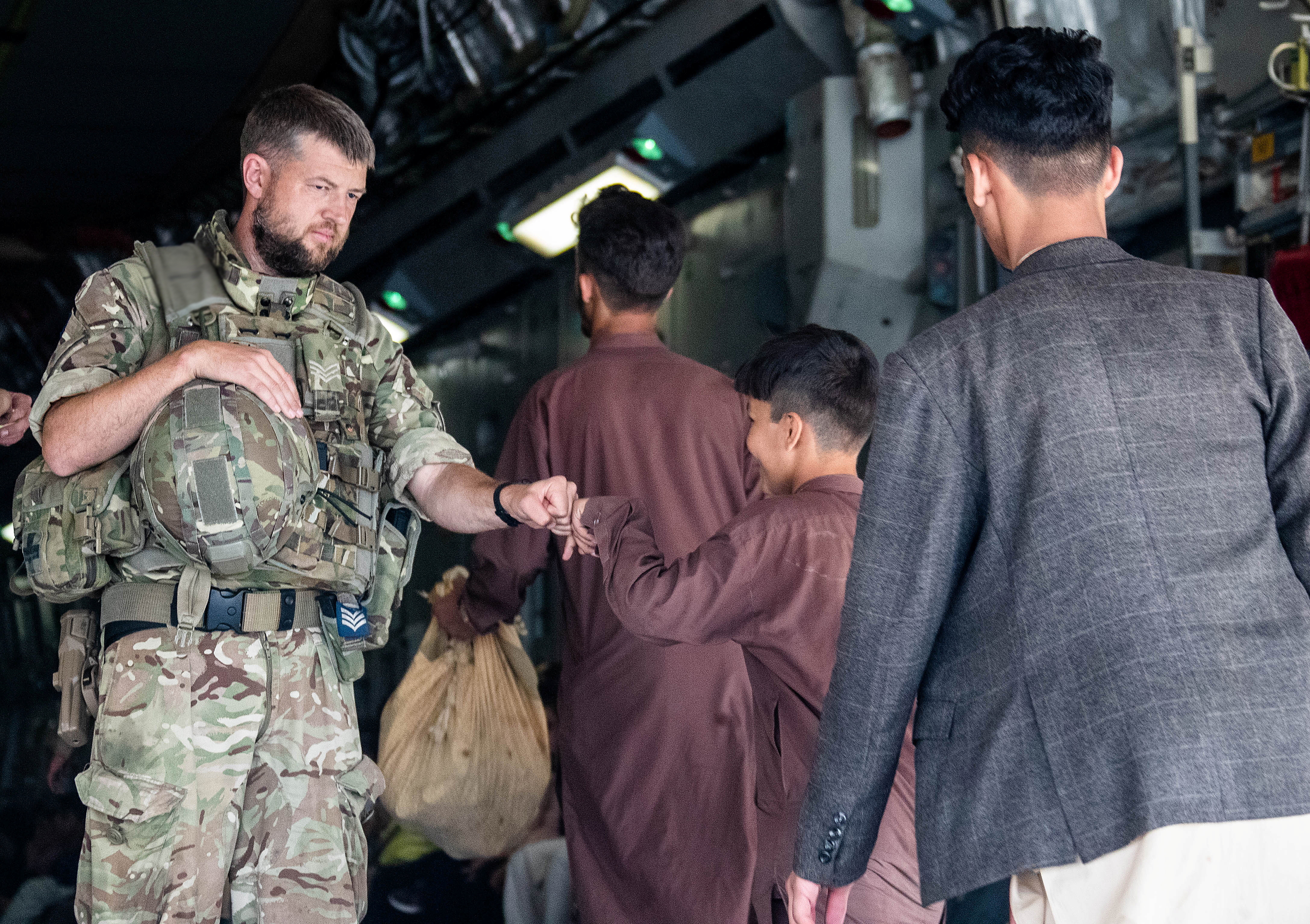 Un miembro de las Fuerzas Armadas del Reino Unido choca los puños con un niño mientras durante la evacuación en el aeropuerto de Kabul, Afganistán, en esta imagen de archivo obtenida por Reuters el 23 de agosto de 2021. LPhot Ben Shread/UK MOD Crown copyright 2021/Handout via REUTERS