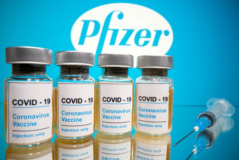 Viales y una jeringa médica frente al logotipo de Pfizer
