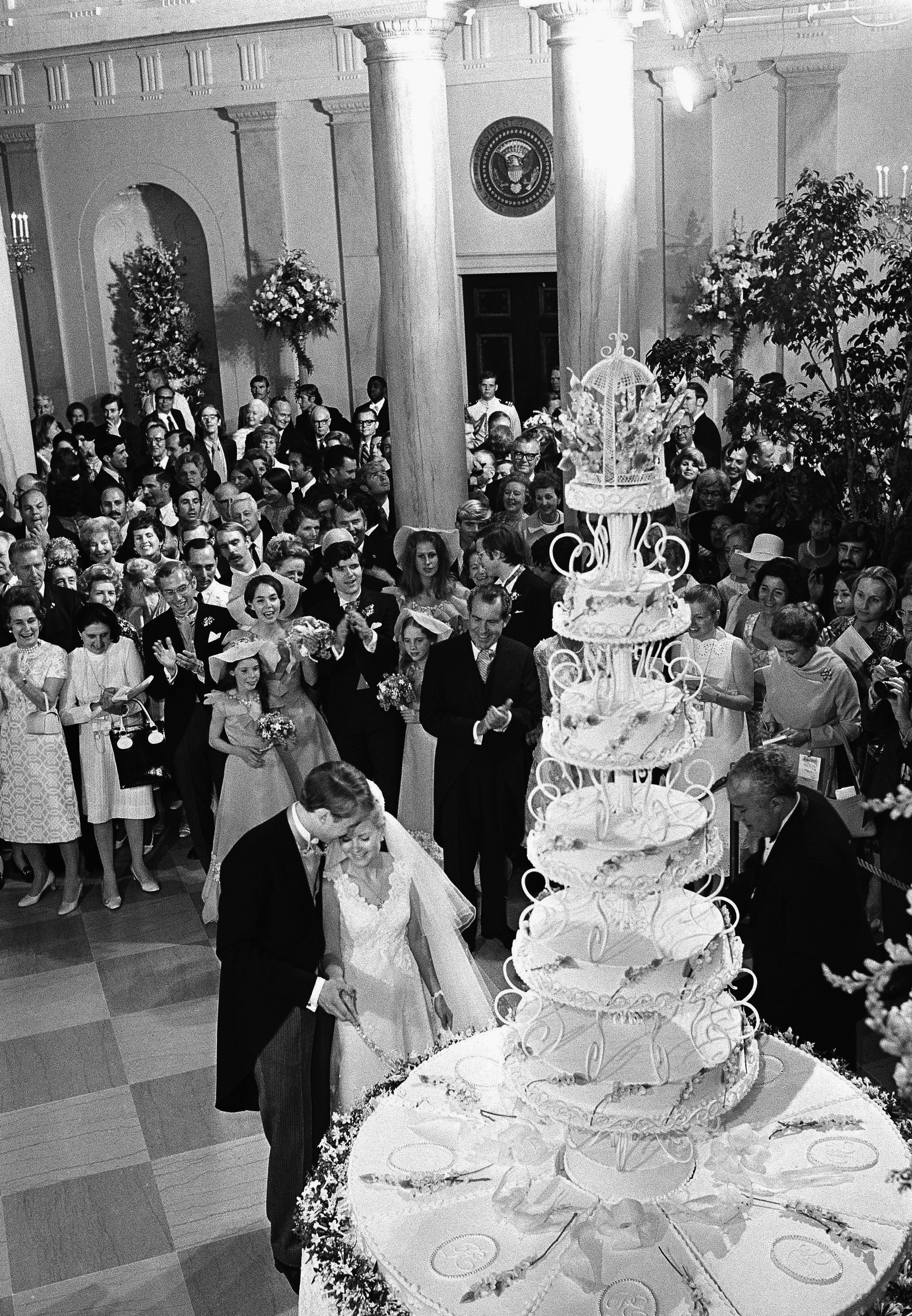 ARCHIVO - El presidente Richard Nixon aplaude cuando su hija Tricia y su esposo Edward Finch Cox, cortan un pastel de bodas gigante en la Casa Blanca, el 12 de junio de 1971. (AP Foto, Archivo)

