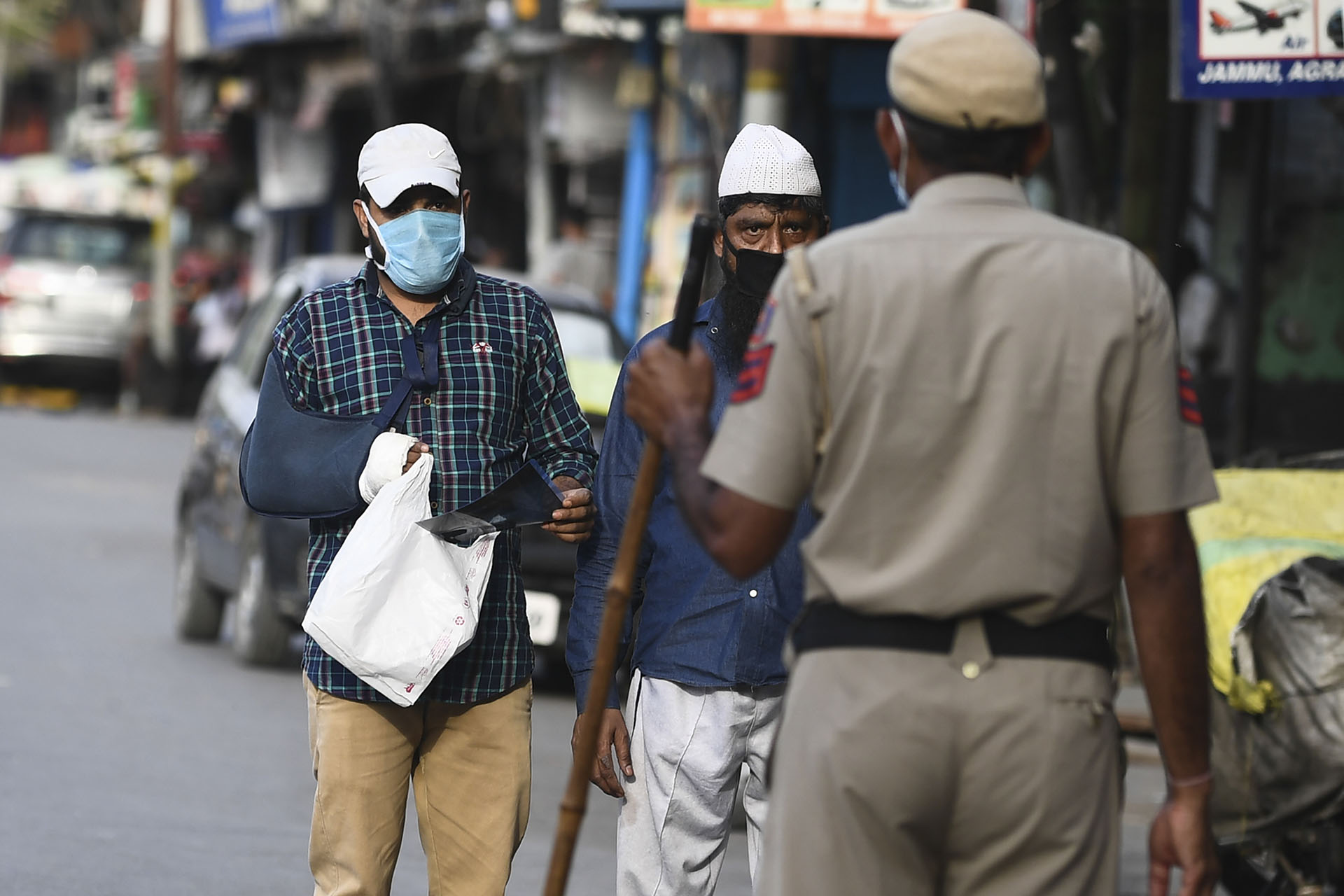 Un oficial de policía interroga a peatones en un puesto de control en el casco antiguo de Nueva Delhi el 23 de abril de 2020. (Foto de SAJJAD HUSSAIN / AFP)