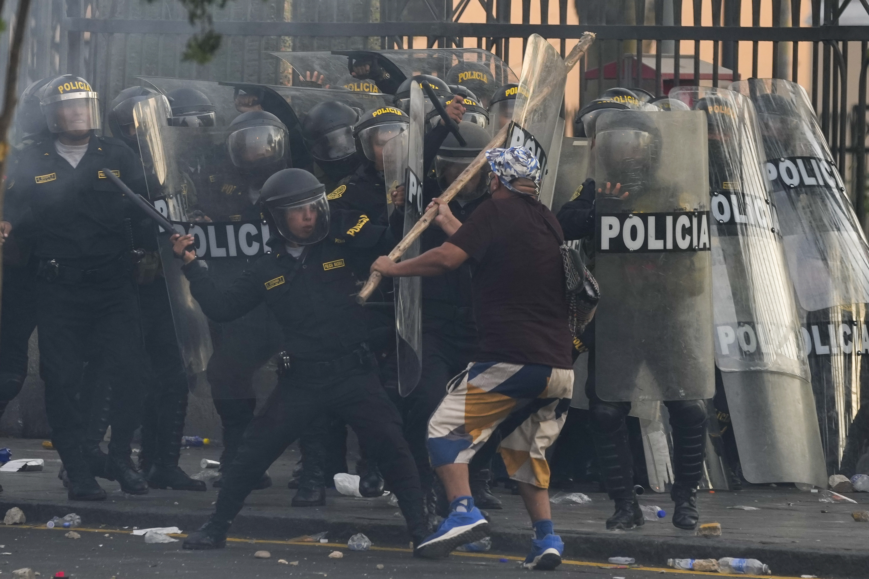 An anti-government protester charges police with a stick during clashes in Lima, Peru, Thursday, Jan. 19, 2023. The protests seek an immediate electoral advance, Boluarte's resignation, the release of ousted president Pedro Castillo, and justice for the at least 48 protesters killed in clashes with the police.  (AP Photo/Martín Mejía)