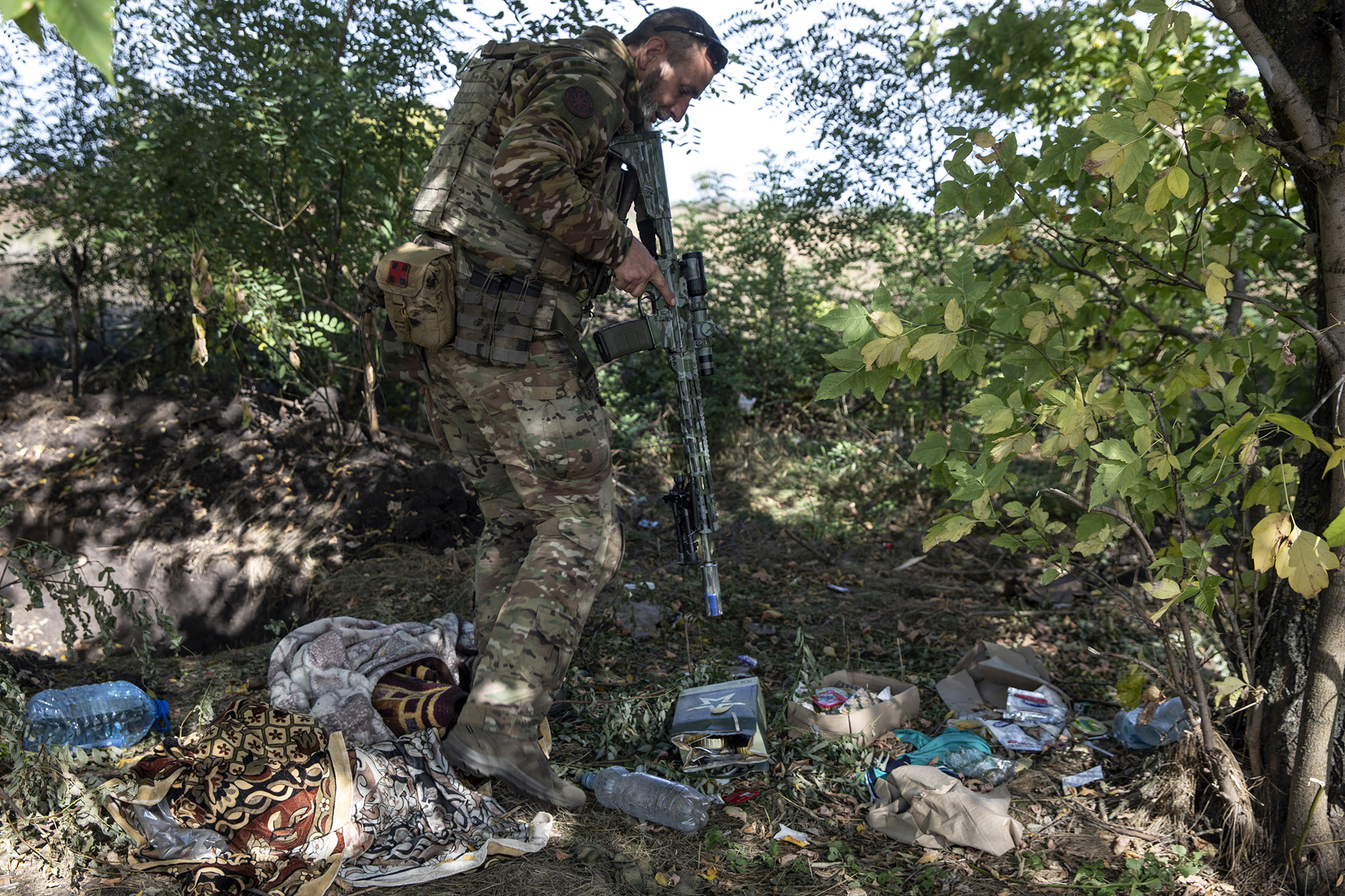 Denys, de 42 años, miembro de la unidad ucraniana Falcon de las Fuerzas de Defensa Territorial de Kryvyi Rih que se hace llamar "Khatib", explora una antigua posición de la línea de trinchera rusa llena de comida en la región de Kherson (Photo for The Washington Post by Heidi Levine)