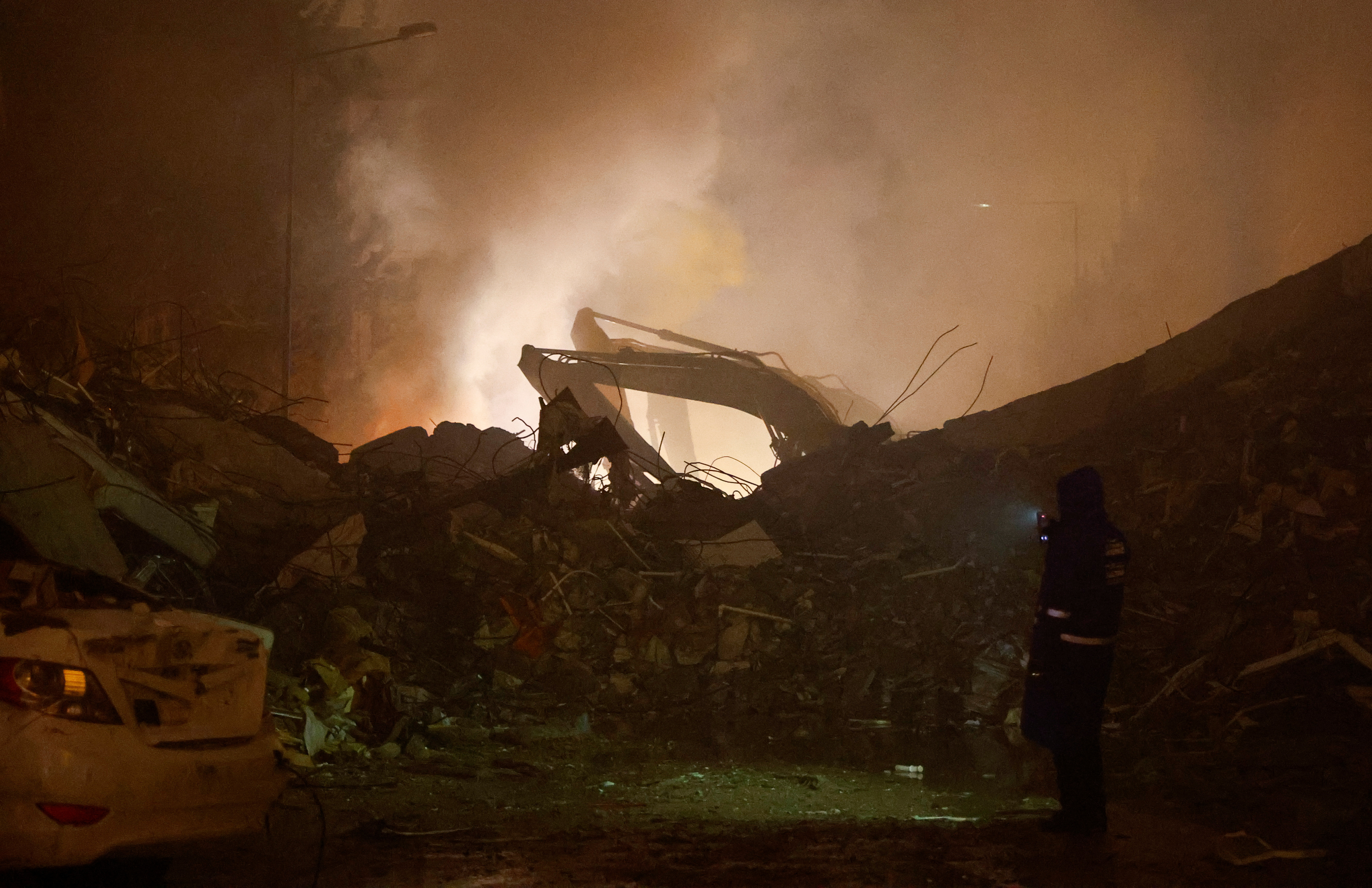 Una persona usa un dispositivo electrónico, junto a los escombros de un edificio derrumbado, luego de un terremoto, en Osmaniye, Turquía, el 6 de febrero de 2023. REUTERS/Suhaib Salem