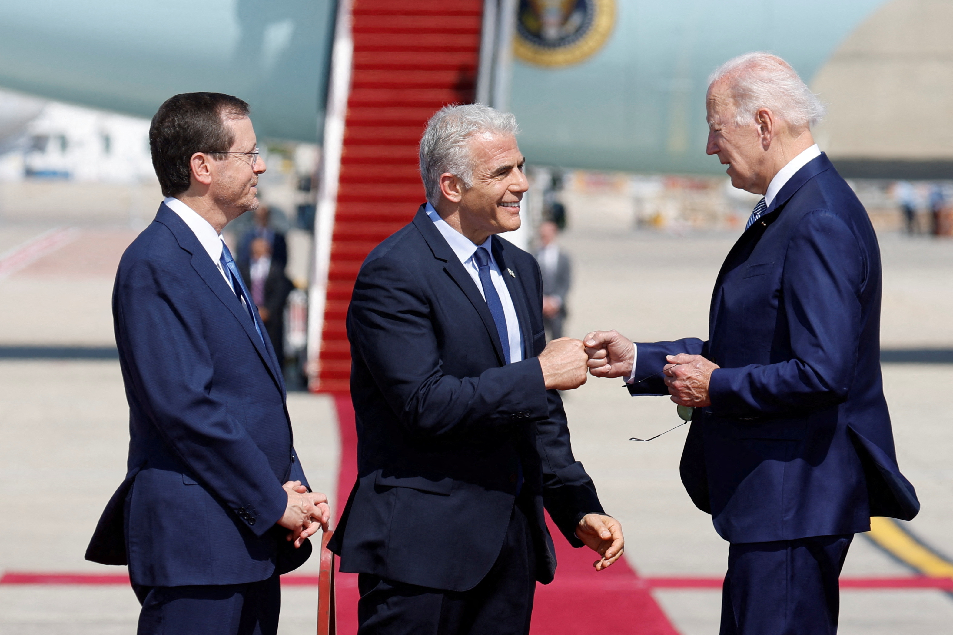 El presidente israelí Isaac Herzog mira mientras el primer ministro Yair Lapid choca los puños con el presidente estadounidense Joe Biden durante una ceremonia de bienvenida en el aeropuerto internacional Ben Gurion en Lod, cerca de Tel Aviv, Israel, 13 de julio de 2022. REUTERS/Amir Cohen TPX IMÁGENES DEL DÍA