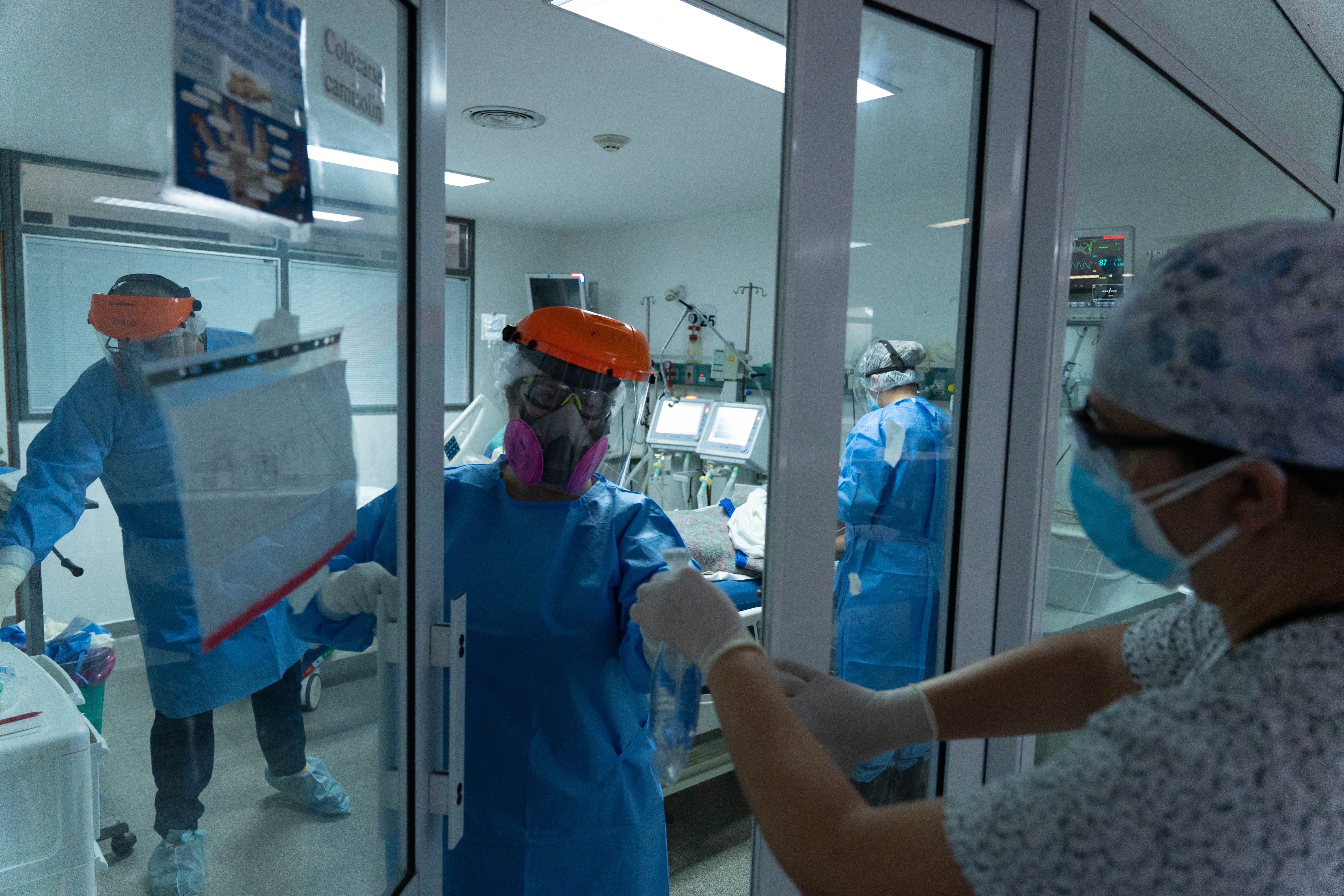 Carina Balasini recibe un instrumento para intubar a una paciente. Algunas enfermeras no entran a la sala para poder acercar las herramientas a los médicos.