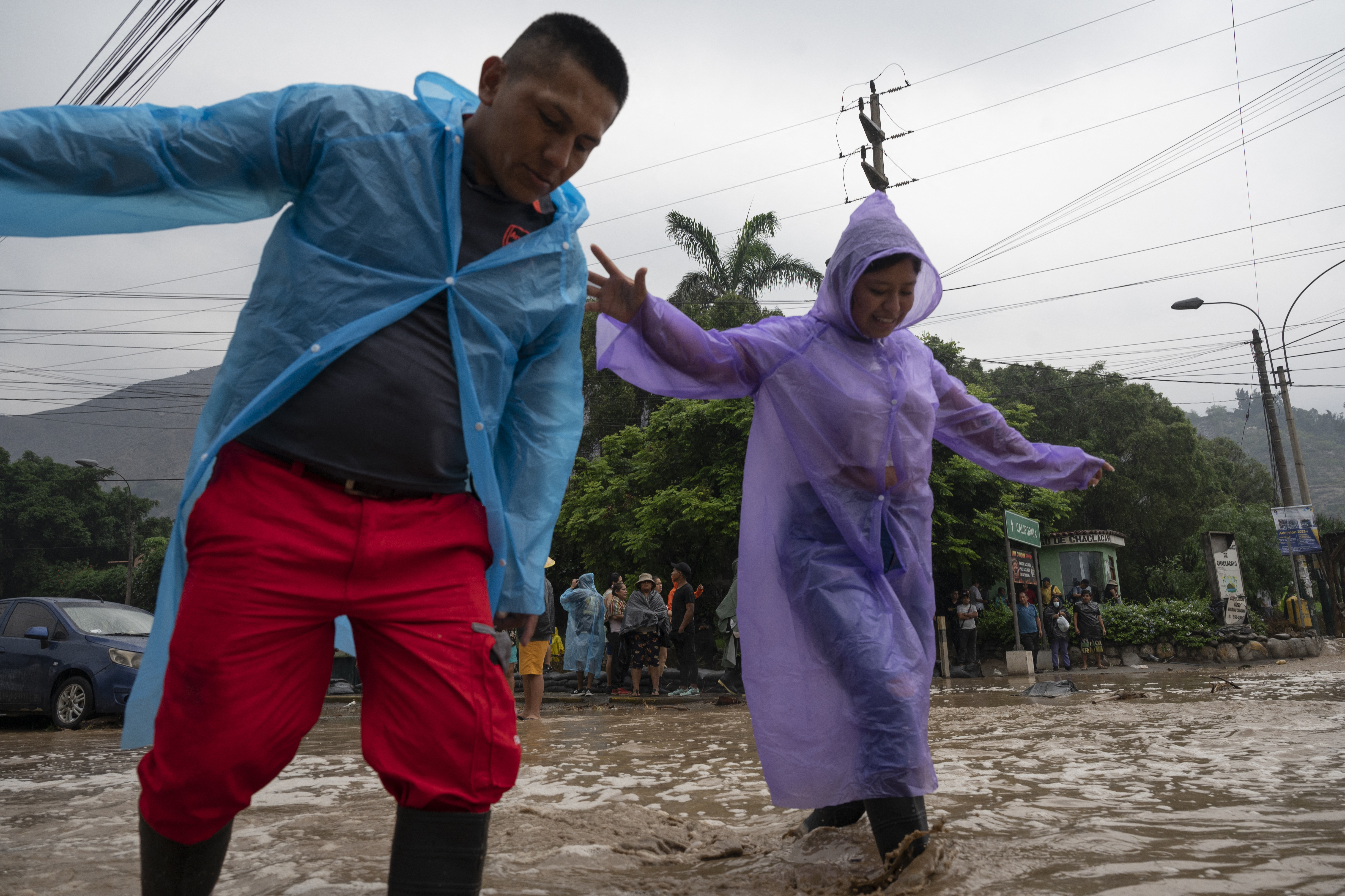 Personas cruzando las vías inundadas por el huaico en Chaclacayo. (AFP)
