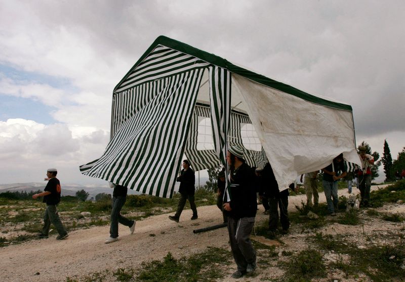 FOTO DE ARCHIVO. Activistas israelíes transportan una tienda de campaña en el asentamiento judío abandonado de Homesh, en el norte de Cisjordania REUTERS/Ronen Zvulun