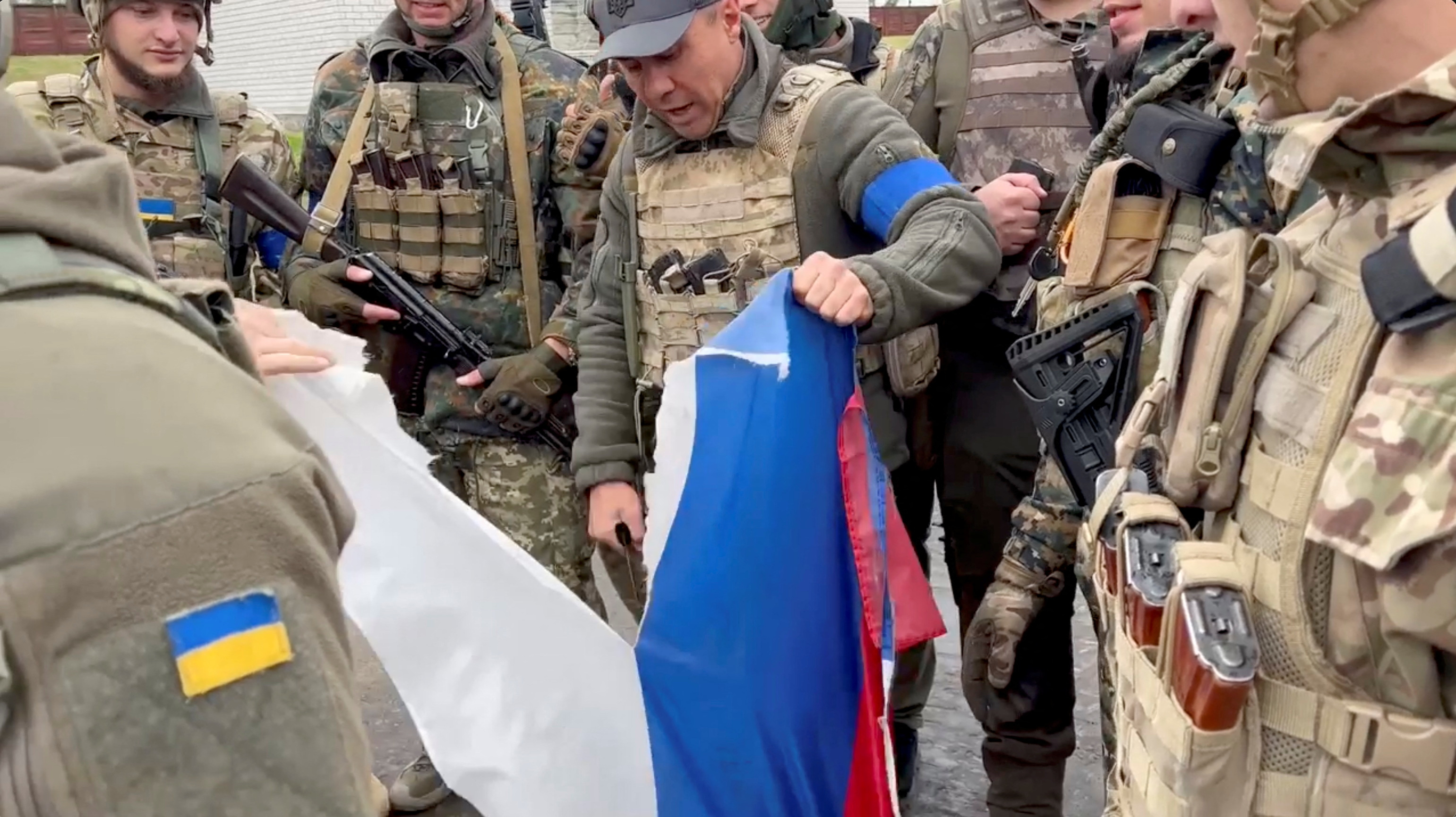 El alcalde del distrito de Derhachi, Vyacheslav Zadorenko, con un grupo de soldados, rompe una bandera rusa en Kozacha Lopan (Facebook/Vyacheslav Zadorenko via REUTERS)