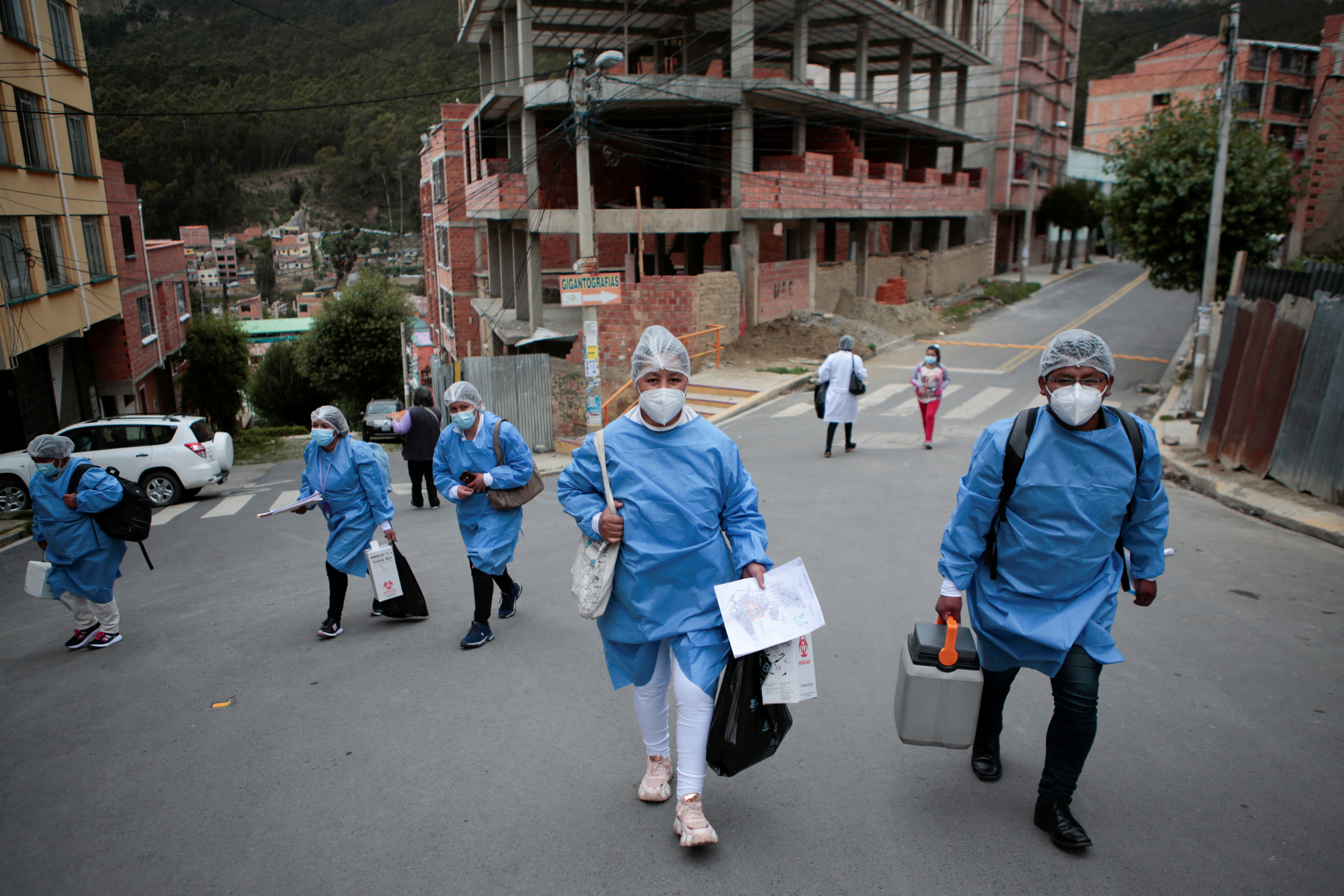 Trabajadores de la salud caminan en la calle durante una recorrida puerta a puerta para vacunar a los residentes contra el COVID-19 en La Paz, Bolivia (REUTERS/Manuel Claure)