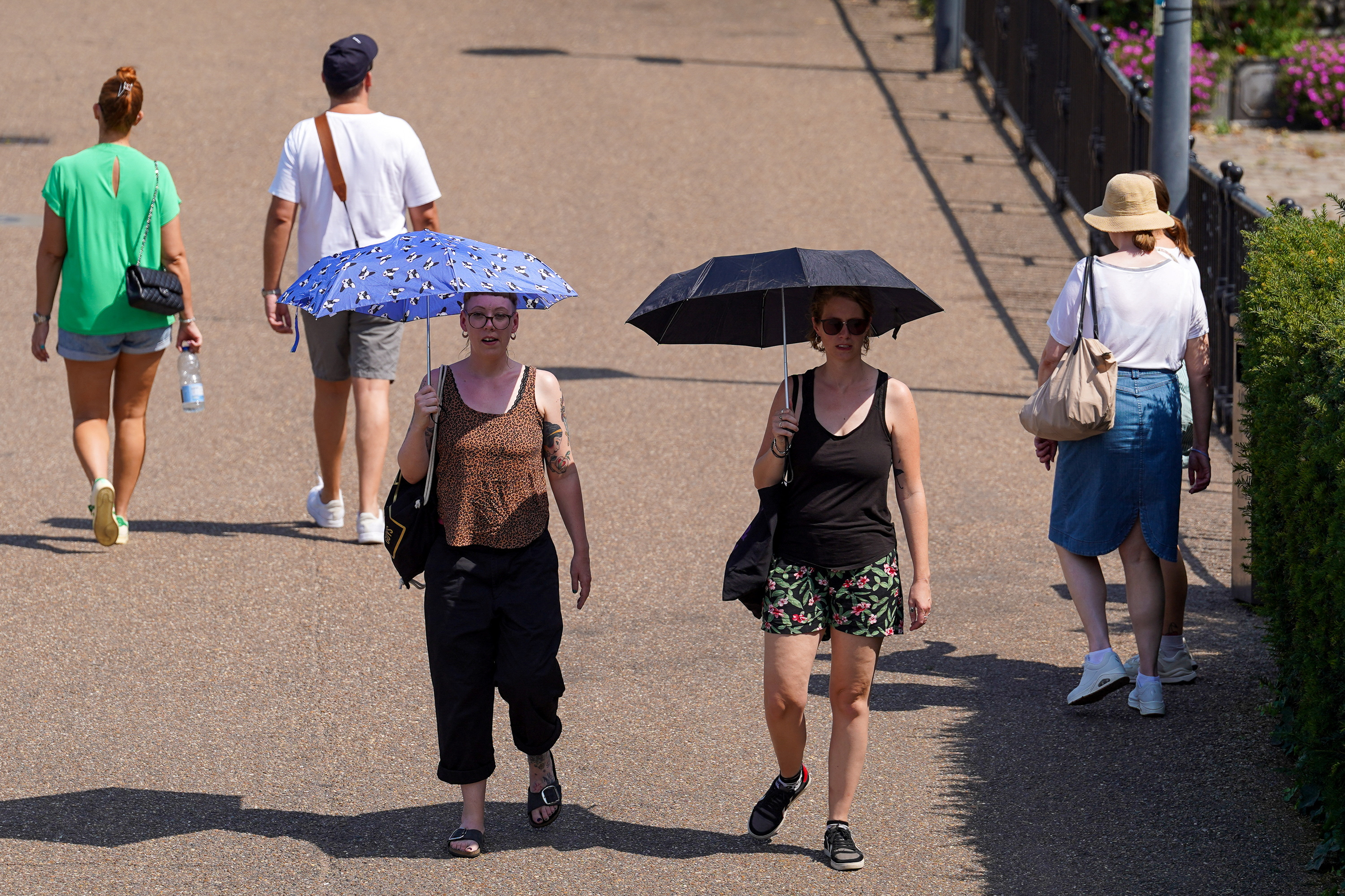 Dos mujeres cruzan el Millennium Bridge protegiéndose de los rayos del sol (REUTERS/Maja Smialkowska)