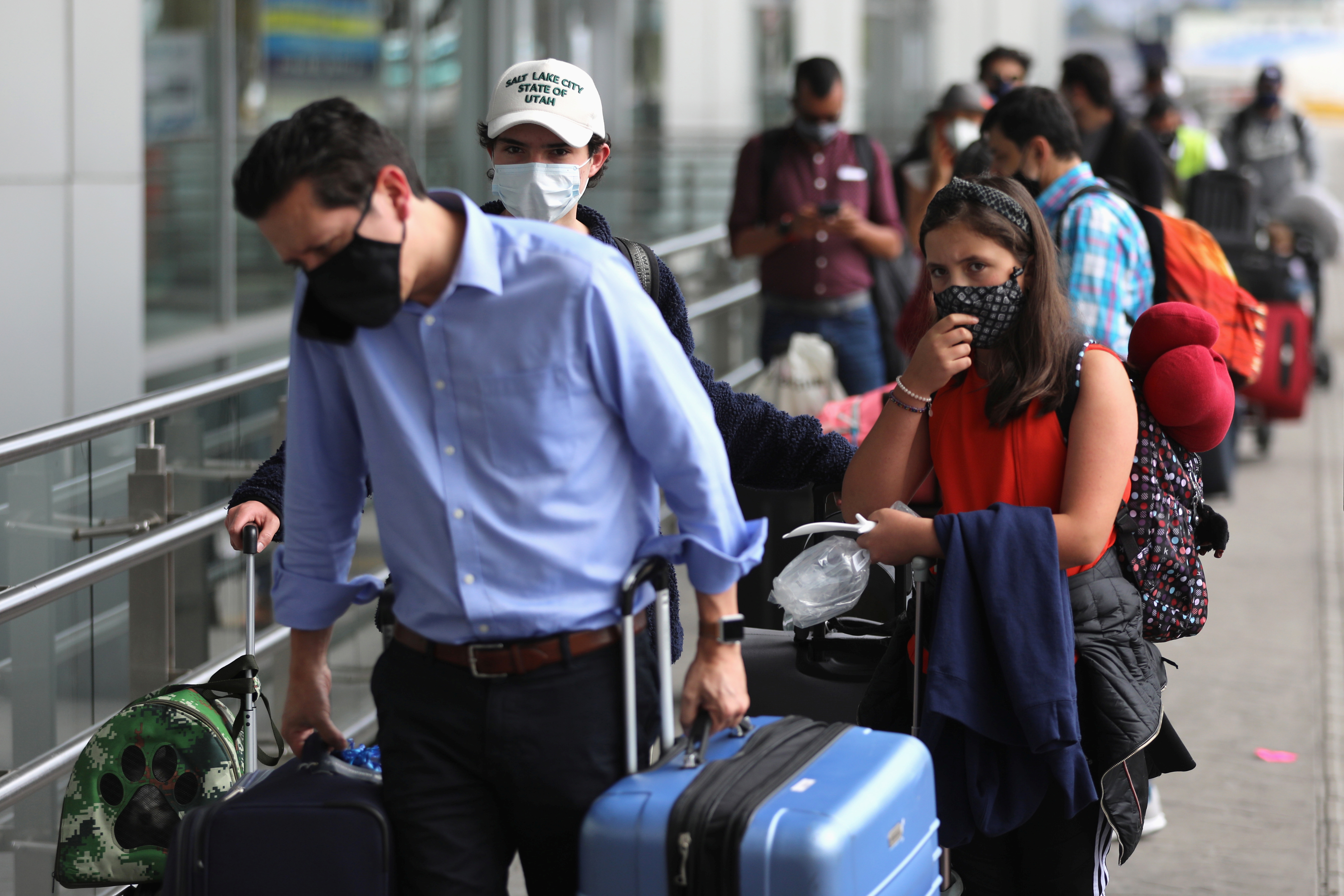Passengers wearing face masks line up to check in at El Dorado airport, after the Colombian government decreed restrictions on flights from the United Kingdom, over fears of a new strain of the coronavirus, amid the spread of the coronavirus disease (COVID-19), in Bogota, Colombia December 21, 2020. REUTERS/Luisa Gonzalez